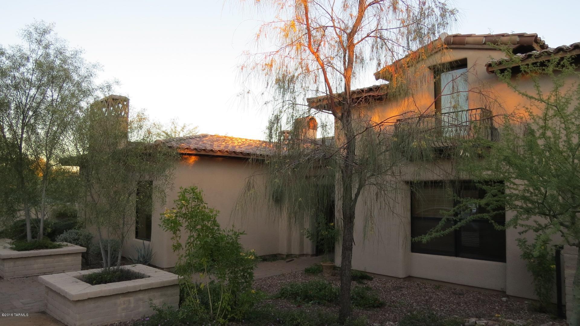 Unique Spanish influenced Contemporary Home in Honey Bee Ridge Estates. The custom wrought iron front gate opens onto a charming, enclosed Courtyard with fireplace. The Main Home is 3 BR/3.5 BA with separate 1BR/BA Guest Quarters, 5 Fireplaces & 4 Car Garage. Living Room features high ceilings, built in bookcases flanking the stone FP & French doors lead to the covered patio.  Features include a Gourmet Kitchen with upgraded SS appliances, island, granite counters, breakfast bar & area, Formal Dining Room with FP and Butlers Area with Wet Bar/Ice Maker, enclosed Arizona Room with Outdoor Kitchen, Bar and fireplace that is perfect for year round entertaining. Fabulous Master Suite, Bath & 2 large Walk In Closets. The rear yard has a Pool with cascading waterfall, Spa & Pusch Ridge Mt views.