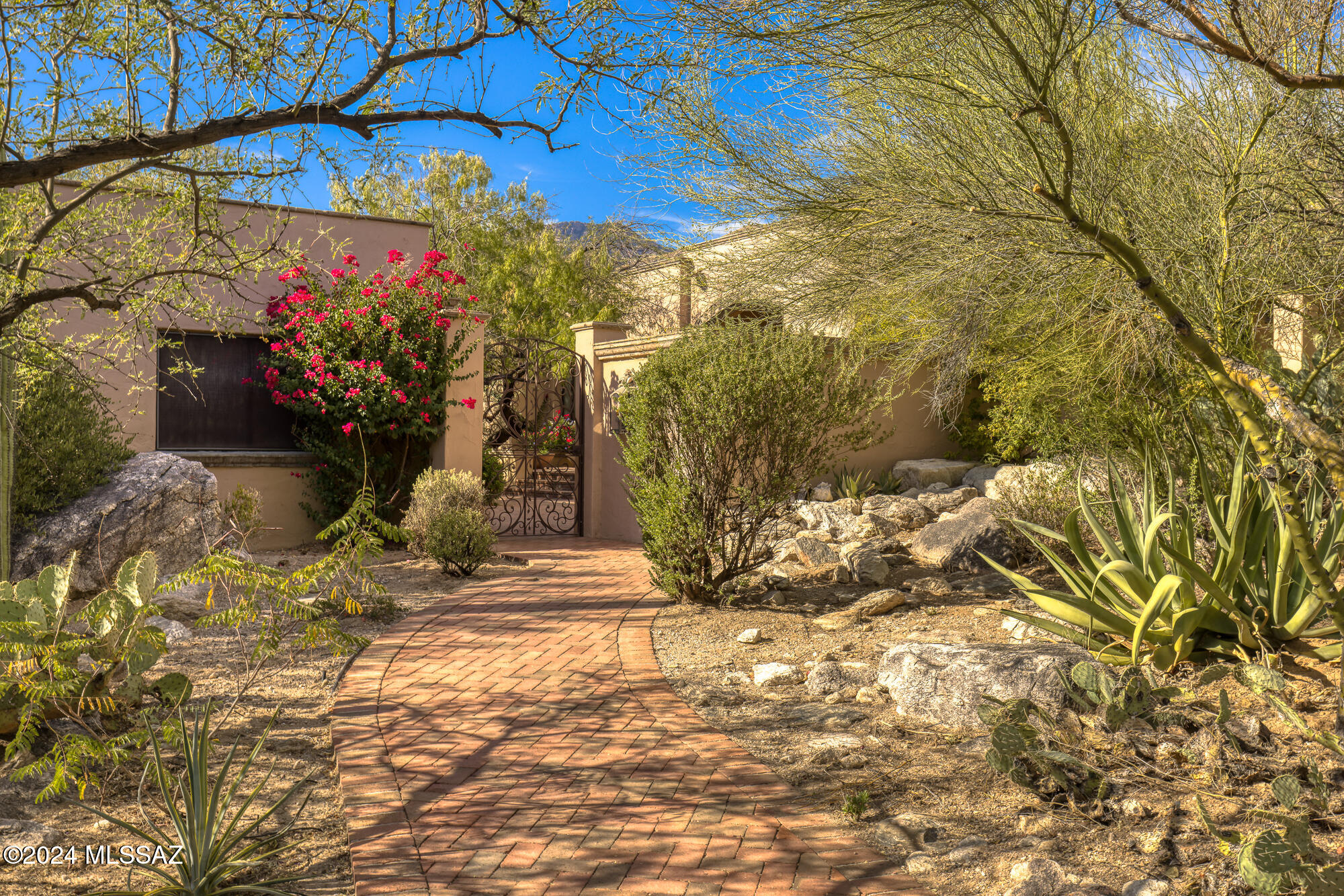 Nestled on a private, 1-acre lot at the top of the Catalina Mountain foothills, this exceptional custom home offers unparalleled desert beauty and up-close mountain views. Located in the prestigious gated community of Canyon View Estates, between Ventana Canyon and Sabino Canyon, this home embodies the best of Tucson's landscapes, lifestyle, & luxury.
Step through a custom entry gate into a serene courtyard shaded by mesquite trees, setting the tone for the bright & inviting interior. The open floor plan is designed to showcase the surrounding beauty with walls of windows, honed flagstone floors, and high-quality finishes throughout. The great room is centered around a striking Cantera fireplace, while the dining area and den offer versatile spaces for living and entertaining The home's deep, covered brick patios wrap around the property, creating a seamless transition to outdoor spaces. Just off the kitchen, an outdoor dining area with a built-in BBQ provides the perfect setting for al fresco meals and gatherings.
The recently remodeled kitchen is a chef's dream, featuring custom cabinetry, Caesarstone and Granite countertops, a Viking six-burner oven and cooktop with a hood vent, and a Sub-Zero refrigerator/freezer. A Bosch dishwasher and microwave add to the modern convenience, while a center island with a wine refrigerator & bar seating complete the space. Adjacent to the kitchen, the dining nook is bathed in natural light & offers stunning views of the desert and mountains. A custom-built buffet provides additional storage and adds a functional yet elegant touch.
The primary suite is a true retreat, featuring a dramatic fireplace, 2 walk-in closets, and breathtaking views. Direct access to a private covered patio, offering a quiet sanctuary to enjoy the natural surroundings. The ensuite bathroom is spa-like in its design, with dual vanities, a large steam shower, and a soaking tub. The second bedroom serves as a luxurious guest suite with a beautifully updated ensuite bathroom, while the third bedroom offers flexible space that can easily function as an office or studio.
The resort-style backyard strikes a perfect balance between natural desert beauty and modern amenities. A Cantera-bordered lap pool is surrounded by native cacti and plants, creating a tranquil setting for relaxation. Multiple private patios and seating areas are ideal for dining, reading, or simply taking in the stunning landscape.
Additional features include a two-car garage with a separate office. With its north-south orientation, the home is bathed in natural light throughout the day.
This property is located just minutes from Sabino Canyon Park, Ventana Canyon Resort, world-class golf courses, fine dining, and shopping, all within the highly regarded District 16 school district. Offering the perfect combination of elegance, functionality, and access to Tucson's most desirable amenities, this home is an exceptional desert retreat.