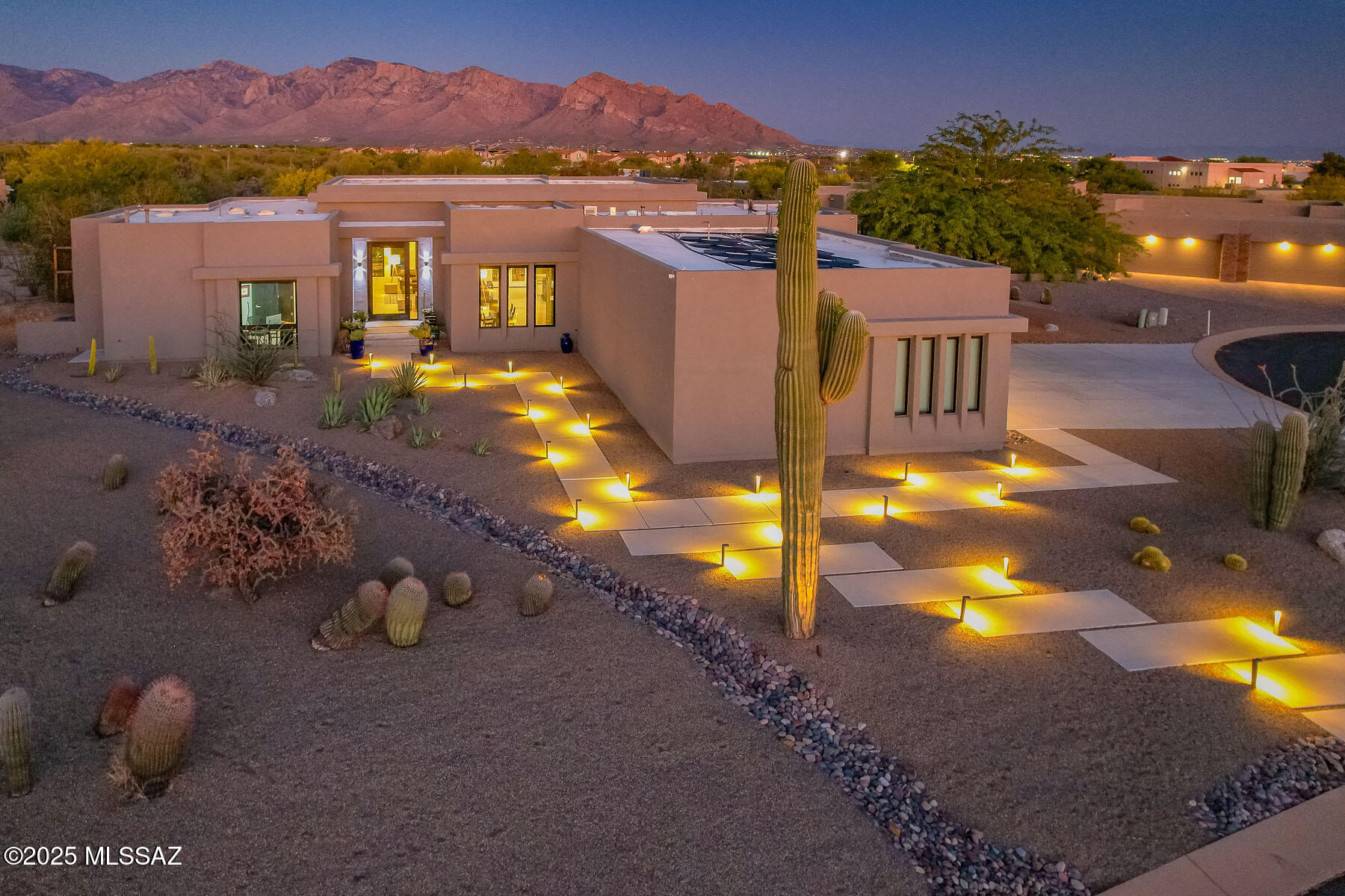 Experience the perfect blend of luxury and modern technology in this small, gated community of Sunset Canyon Estates in Oro Valley. Contemporary, highly upgraded 4BD/4BA (3,355 sf) home on .84 acres showcases a dramatic lighted walkway, 5'x10' pivoting glass entry door, impressive Gathering room and formal Dining room with 450-bottle glass wine display case. Resort-style yard boasts a Travertine stone patio, solar heated pool with raised spa & decorative stone waterfall, stone finished firepit, granite-top grill station, large Botanical Center beyond, plus breathtaking sunsets upon the Catalinas. Richly finished details throughout include 18''x36'' porcelain tiled floors in main living areas, granite counters in kitchen/laundry/baths, walk-in closets in carpeted bedrooms, 1-3/4'' Alder doors plus vogue crystal light fixtures. Expansive Gathering room is highlighted by soaring, recessed ceilings and walls of windows overlooking the yard and mountains. Spectacular gourmet kitchen boasts dual islands with level 4 Alaska White Granite, Charcoal Quartz waterfall edge island with bar seating, counter-to-ceiling glass mosaic tiled backsplash, top-of-the-line appliances, dining nook plus walk-in pantry. Elegant Owner's Suite hosts a luxurious bath featuring dual sink vanity, soaking tub, tiled walk-in shower and large custom closet. Two additional en-suite guest rooms plus 4th bedroom (ideal as an office). Additional amenities include spacious laundry with sink, light filtering skylights, automated window coverings, central vacuum, fire suppression, whole house surge suppressor, smart panel, security features and more! Botanical Center at rear of property offers a meandering, gravel walking path showcasing native plants, olive & bottle brush trees, 250-year-old saguaro cactus plus smaller cacti for your viewing pleasure. Three car garage hosts a sectioned off third bay with 10-foot cabinetry and countertop. Perfect for the most discerning buyer!