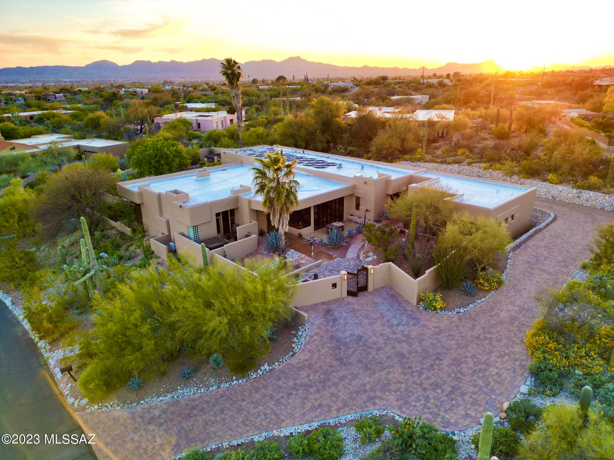 This quintessential David Tyson designed contemporary style retreat invites you to experience unrivaled views and serenity. This home embodies an ideal combination of bold and unique style, clean modern lines, exposed wood ceilings and low-maintenance concrete floors. The floor to ceiling windows bring the natural beauty of the outside in, with spectacular mountain and city views, while thoughtfully placed overhangs protect from direct sunlight.  The open-concept floorplan features three distinct bedroom wings, offering ultimate privacy for family members or guests. Both main house HVAC units have been replaced in May 2023. The primary suite features a sitting area and fireplace with spa-like ensuite, dual walk-in closets with custom California Closets systems, and a private patio with hot tub for sunset Catalina Mountains views. At the core of the home is an expansive living space, ideal for entertaining, featuring two distinct dining areas, and a luxurious chef's kitchen, complete with top-of-the-line appliances and a butler's pantry. The stunning recycled glass countertops that are non-porous, resistant to stains bacteria and heat and are easy to clean. Intentionally tucked away in the butler's pantry is a steam oven, warming drawer, coffee station and ample cabinetry and additional countertop space. Utilize the separate wet bar with wine fridge and ice maker to host gatherings, large or intimate. with a A 15-ft foldaway glass wall blurs the boundaries of indoor-outdoor living, connecting you with nature, the vast mountain scape and beautifully landscaped, completely walled-in private courtyard.  Immerse yourself in the surrounding nature and unwind on the elevated covered south patio, next to the koi pond water feature overlooking the pool and spa, which draw your gaze toward the twinkling city lights. In addition to expansive main house, this premium lot offers a 797 sqft guest house w/ private entry, kitchenette, living room, bedroom and ensuite bathroom, complete with washer/dryer hookups.  Just moments away from La Encantada shops and restaurants, Banner Medical and The U of A, foothills hiking trails, top-rated Catalina Foothills schools, and much more. Schedule a private appointment to view this one-of-a-kind masterpiece.