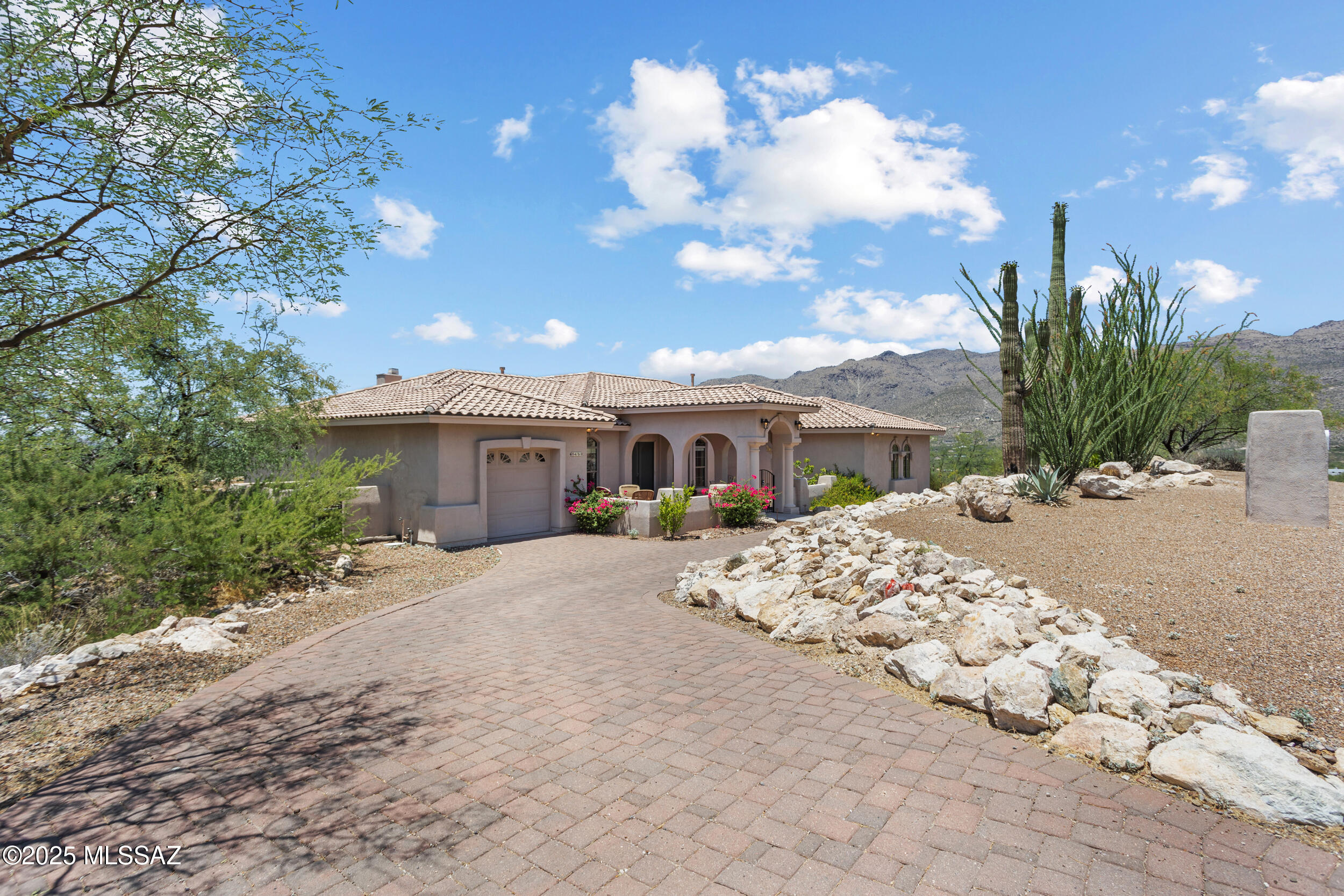 Perched on an elevated lot in Agua Caliente Estates, this stunning home showcases breathtaking mountain, desert, and city views from every room. Set on over an acre of pristine Sonoran landscape, it offers privacy and serenity just minutes from Tucson amenities. Grand windows fill the home with natural light. The office features lavish custom built-ins and a bar. The primary suite includes a large walk-in shower and soaking tub. The backyard offers a built-in spool (spa/pool combo) for year-round outdoor enjoyment with awe-inspiring sunsets. This home features a third-car garage expertly transformed into a fully equipped woodworking workshop with a dedicated ventilation system, ideal for hobbyists & professionals alike. Own a home that celebrates the beauty of the Southwest.