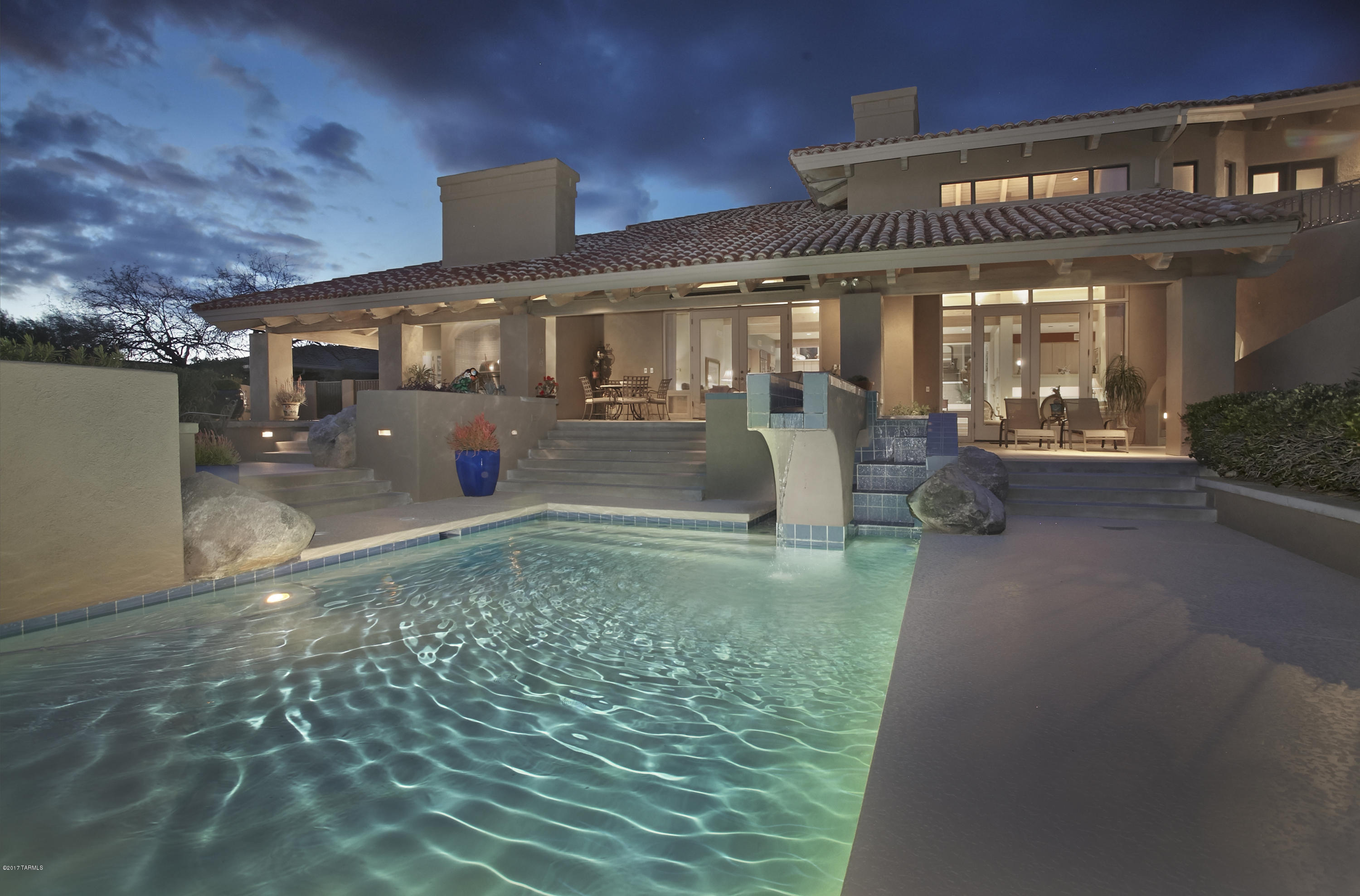 A contemporary architectural masterpiece with show stopping city views located in one of Tucson’s premier gated communities. The varying levels & stunning design features create a dramatic interest to the interior, while the porch, terraced patio & pool provide an unsurpassed area for outdoor entertaining above the twinkling city lights. The open floorplan w/walls of windows includes a master bdrm suite w/a sitting area, library, luxurious bath & an enormous closet, an inviting guest suite w/city light views, 2 private home offices, a formal dining rm, a remodeled gourmet kitchen w/new stainless appliances & granite and a dramatic living room w/22ft ceilings adjoining a family rm w/equally high ceilings & double sided fireplace. Large exercise rm w/roof deck provides the ultimate home gy