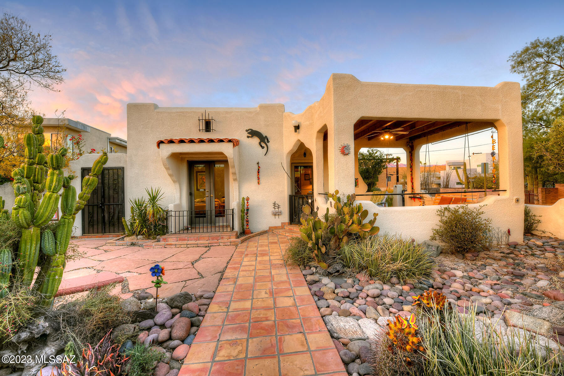 A wonderful compound with 2 very charming historic Spanish-Moorish bungalows located in the Sam Hughes neighborhood, built in 1927 and 1929. The property exudes character and warmth, starting with a welcoming courtyard & covered patio. The main home, spanning 1459 sq ft, and the secondary home, at 787 sq ft, have undergone loving restoration & upgrades while maintaining their original charm.
Key features of the main home include a renovated en-suite primary bedroom with a double sink and walk-in shower, multiple living spaces including a living room, dining room, and a separate family room. The upgraded kitchen boasts newer appliances, countertops, and ample storage, connecting seamlessly with the dining area. The family room stands out with wood plank and beamed vaulted ceilings, offering a cozy ambiance a picturesque views of the yard and gardens through walls of windows. The second dwelling is equipped with a living room, a charming, remodeled kitchen, a bedroom, a full bathroom, and a second bedroom used as a den. It also features a covered patio/Arizona room. The property sits on a large walled-in corner lot with off-street parking, offering both privacy and convenience. The yard is a retreat with multiple covered patios, sitting areas, and artistic garden spots, providing a delightful surprise at every turn. The location is highly desirable, just a few blocks from the University of Arizona, restaurants, the Modern Streetcar, Himmel Park, and more. Notably, the property is listed on the National Historic Register, which can result in a 35-45% reduction in property taxes for owner occupants. Overall, this description highlights a unique and meticulously maintained property with a perfect blend of historic charm and modern amenities.