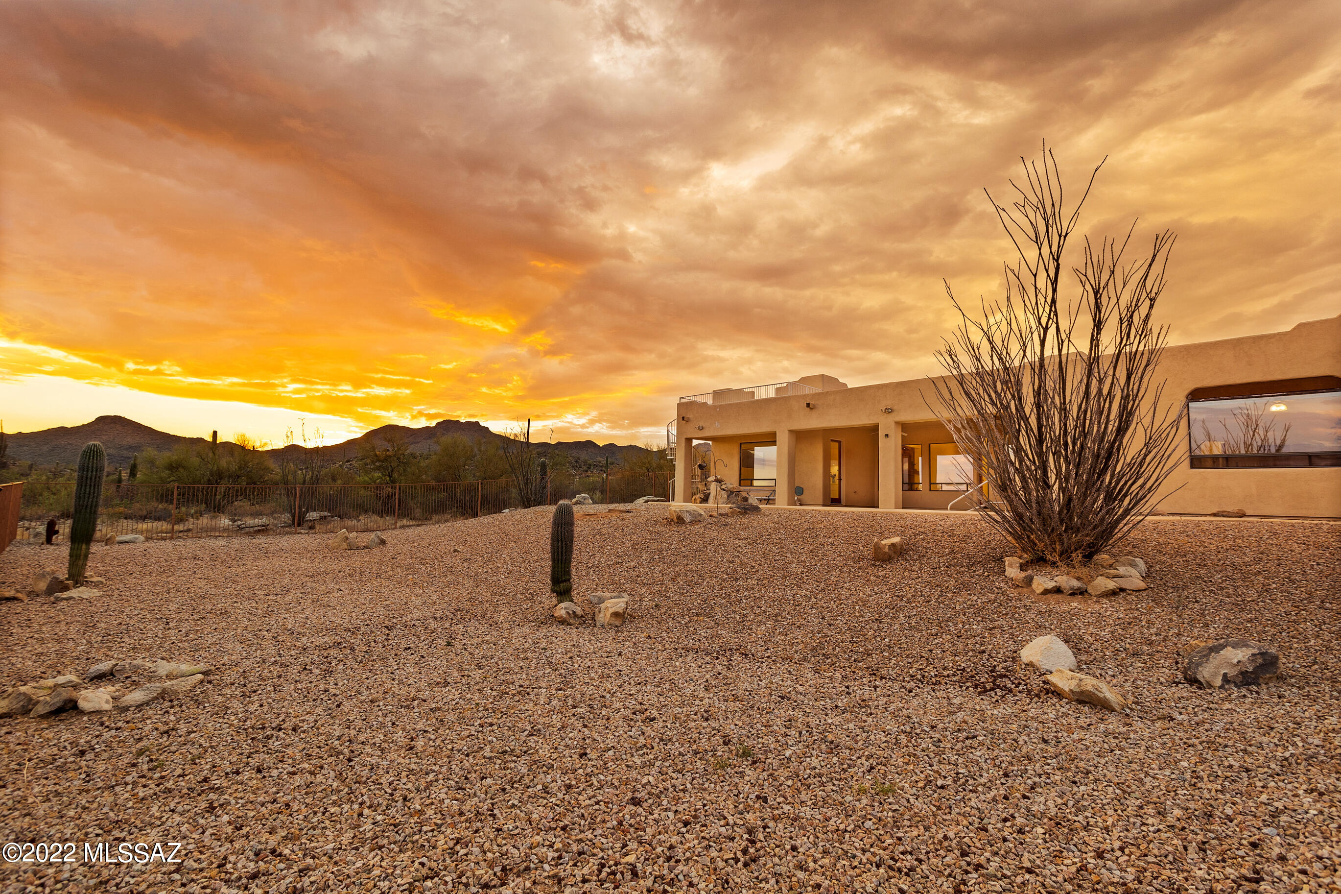 Incredible custom home w/pool on 5 acres (no HOA & owned solar) nestled in the Tortolita foothills offers terrific multi-gen living w/space & privacy for all! Drive through custom gated entrance past dramatic rock formations to this private property that boasts unobstructed panoramic views. Split bedroom plan with TWO master suites, each w/ensuite bath & private patio access + 2 additional BRs, a third full bath, powder room & huge bonus room (home theater, game room, or home school?)  Gather in the great room w/gas-log FP open to chef's kitchen w/custom hickory cabinets, SS appliances, walk-in pantry, granite slab tops + a span of lit display cabinetry below curved breakfast bar. Generous dining nook + adjacent formal dining. Primary master suite occupies one wing w/seating area, walk-in shower w/multiple heads, soaker tub & custom cabinets. Guest wing offers 2nd master w/lg walk-in shower + 2 additional bedrooms, all with beautiful mountain views. Oversized 4-car garage (4th stall walled off w/HVAC for shop or studio) leads into large laundry/mud room next to kitchen. From the covered south-facing patio, you'll marvel at Catalina Mt sunrises and Tucson Mt sunsets. Enjoy blazing sunsets or star-studded night skies from viewing deck with spiral staircase. Imagine the possibilities in your own private paradise! Plenty of room to expand for the equestrian lifestyle, a guest home, or RV garage.