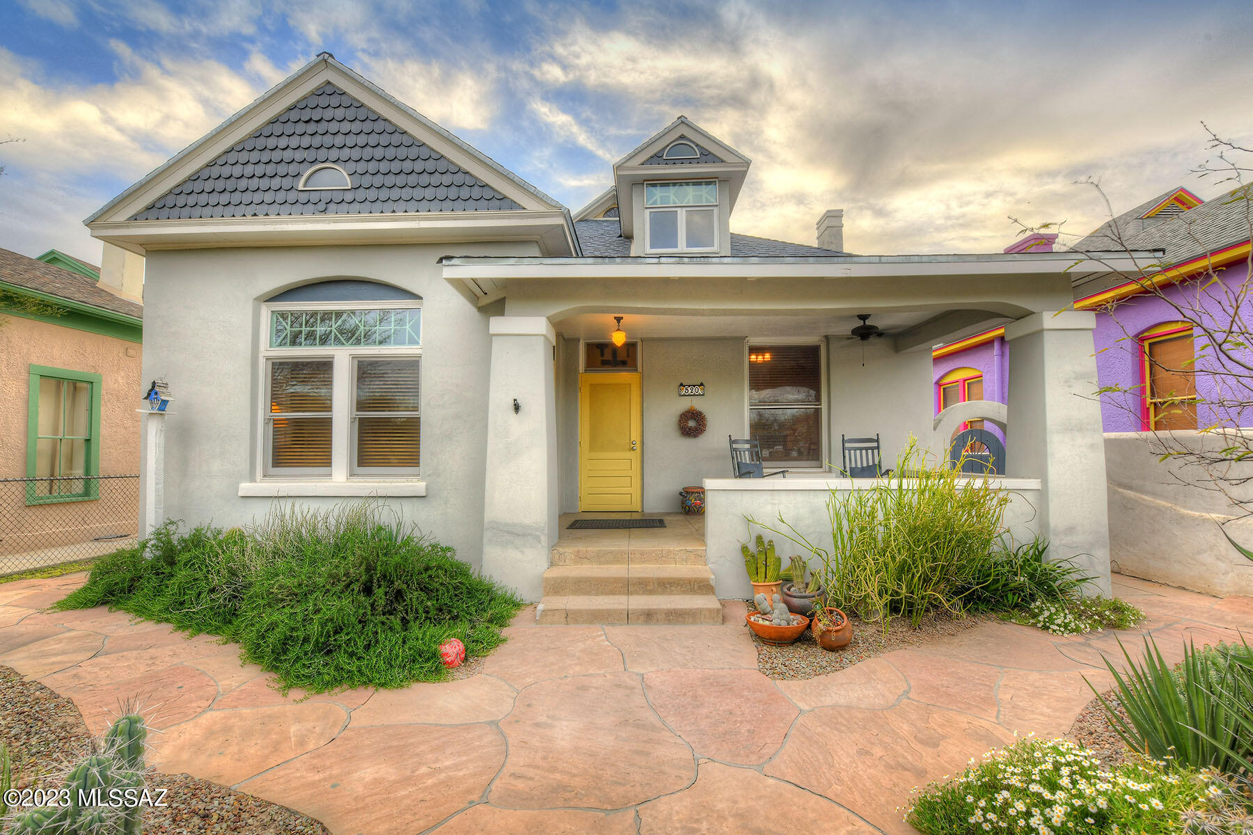 The Queen Anne style is known for its ornate details and this particular home built in 1902, in Armory Park seems to be a prime example. Beautiful woodwork unique to the era and built-ins have been preserved and adds to the charm and character of this home. The high ceilings and fir and oak floors are features that are highly sought after in historic homes. The renovation of the bathrooms and modernization of the kitchen are a perfect blend of old-world charm and modern amenities.  The primary bedroom has an upgraded ensuite bathroom. The 2nd bedroom is used as an office.  The upstairs space is spacious and open, providing ample room for various uses. The guest house studio has an open floor plan, Saltillo tile, large bathroom, kitchen with an eat in area. Newer HVAC Systems. The separate guest home offers a comfortable and inviting space for guests, additional living space or vacation rental, adding versatility to the property.
The outdoor space is private and well-maintained, with a large covered patio, water harvesting, fruit trees, and unique desert plantings and specimens create a sweet desert oasis. The location of this Queen Anne home is perfectly situated to Downtown and the Modern Street Car, providing convenient access to urban amenities and attractions.
The property also boasts tons of off-street parking, an electronic gate, and a carport on a large lot w/ access to the alley. Historic Neighborhood offers a tax credit for owner occupied residents.