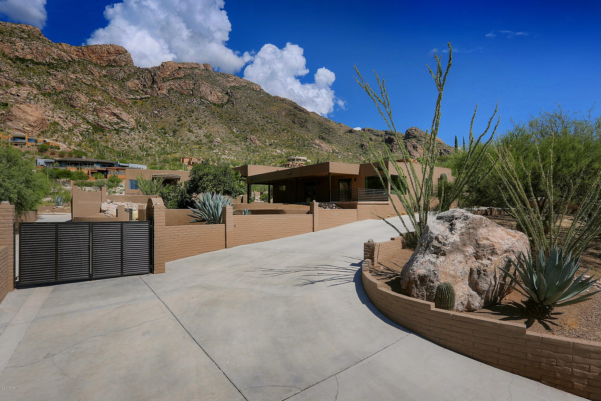 Completely remodeled contemporary home at the base of the Catalina Mountain range, overlooking Tucson city lights. Enter through the pivoting glass door into a great room with a wall of glass looking directly onto the mountains.  Main house boasts 4 bedrooms including the master suite with a spa-like bathroom. Views from all rooms!  Perfect for entertaining, this home has an open floorplan that flows onto the large covered patio with newly installed built in BBQ area and family sized swimming pool. Step across the grassy and citrus filled yard, which is low cost with your own personal well, to the large guesthouse (over 1000 sq ft) which features its own full sized kitchen, 2 baths, garage and laundry with additional space for workshop or exercise room.