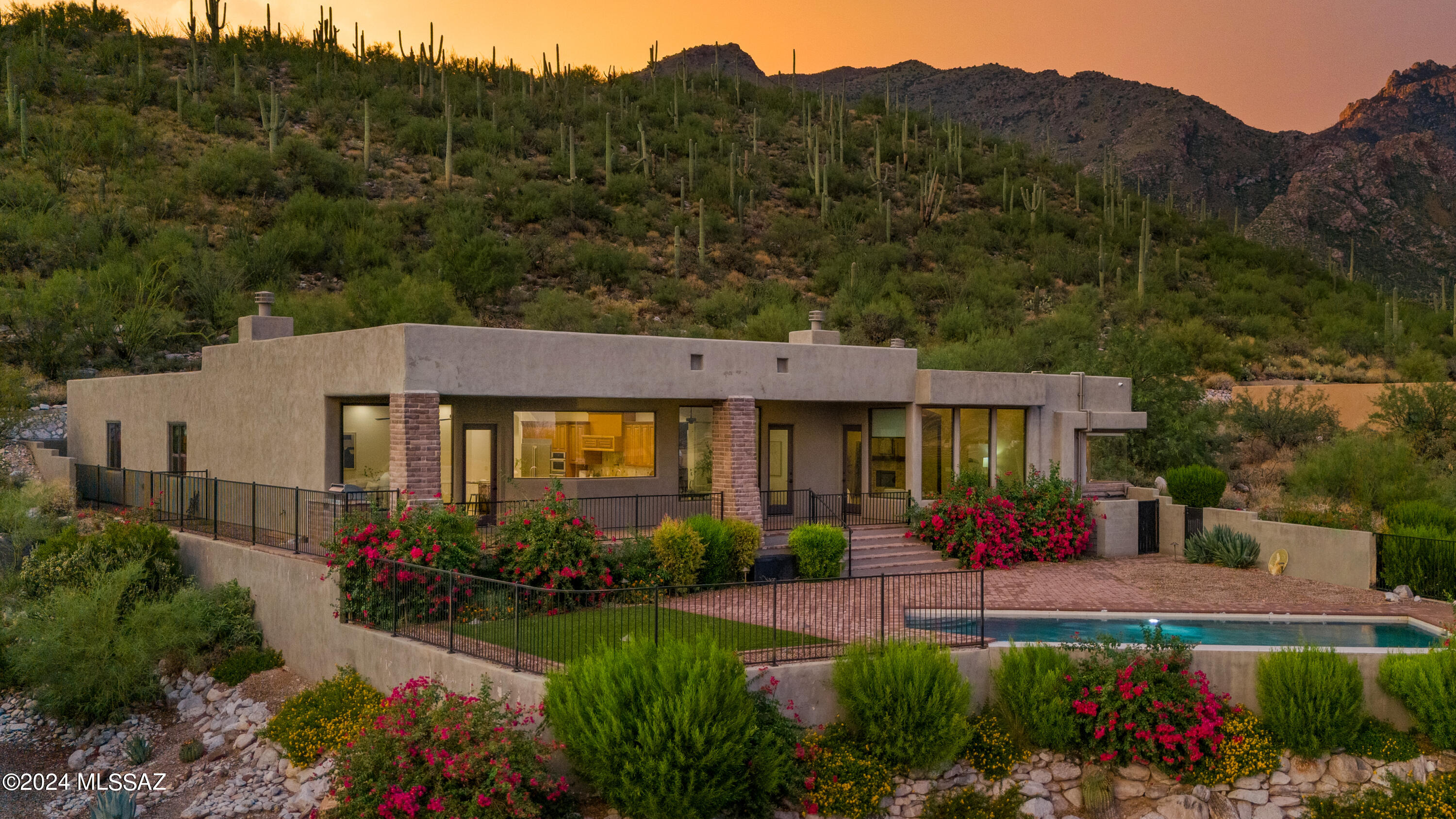2016 custom desert contemporary residence on an elevated homesite in popular Alta Vista.  This 5-bed/5-bath home has sensational views of the city, mountains, & sunsets on a saguaro-studded lot.  Minutes from district #16 schools, Ventana Canyon Country Club, Sabino Canyon, Whole Foods, & more. Soaring 12' ceilings, walls of windows, wood-beam ceilings, natural stone, & light, airy spaces set the tone for this move-in ready home. Captivating views from every window of the city below & the mountains beyond. The mature desert landscape is bursting w/ color as you ascend the driveway lined w/ pavers. Large motor court & private entry w/ a custom wrought iron front door.  Exceptional city views greet you as you enter this open & inviting space with a stacked stone fireplace...CONTINUED The kitchen/great room/dining area has a wood-beamed ceiling, a Cantera fireplace, & a large frameless window in the kitchen that showcases the spectacular views from this high vantage point. The kitchen is complete w/ a center island w/ a breakfast bar, a prep sink, custom pendant lights, custom-built cabinetry, & SS Electrolux Icon appliances. Additional features include double ovens & a 6-burner gas cooktop w/ custom wood hood vent & pot-filler, granite counters & travertine backsplash. The dining area is positioned to capture impressive views & corresponds to the outdoor space for ease of enjoying indoor & outdoor living. The built-in BBQ is conveniently located just outside the kitchen. Enjoy the best of Arizona living from a big backyard with plenty of space without the upkeep. A massive, deep-covered patio lined with w/pavers spans the back of the house. This magnificent outdoor space is enclosed w/ a view fence. A gorgeous pebble-tec pool with a negative edge is surrounded by brick pavers & a space w/ low-care turf. Vibrant desert landscape pops with color but requires little water. The exceptional owner's suite is spacious yet warm & intimate, w/ a stacked stone fireplace, & new wood-look tile. Oversized windows display unobstructed mountain views from the quaint sitting area during the day & city lights at night.. Bright & open owner's suite bath has an exquisite frameless corner window at the soaking tub capturing exceptional views. Additional owner's suite bath features include a dual sink vanity, custom cabinetry, a separate shower, & a huge walk-in closet with w/custom built-ins. One bedroom, which could be an office or nursery, is adjacent to the owner's suite near the powder room. The west wing of the home houses a pre-wired theatre room ready for a home theatre/gaming room, an exercise room/yoga room, or whatever you may need. In addition, there are 3 en-suite bedrooms. One of the bathrooms has hall access as well. Next-level laundry room has a top-of-the-line washer & dryer, tons of cabinets for storage, counter space & a sink.  Oversized garage w/ epoxy floors has plenty of room for storage. Incredible foothills location w/the best lifestyle Tucson has to offer.  Top restaurants, shops, grocery stores & fitness options are minutes away.  For nature lovers & hikers, access incredible trails just moments from your front door & get to Sabino Canyon in a matter of minutes.