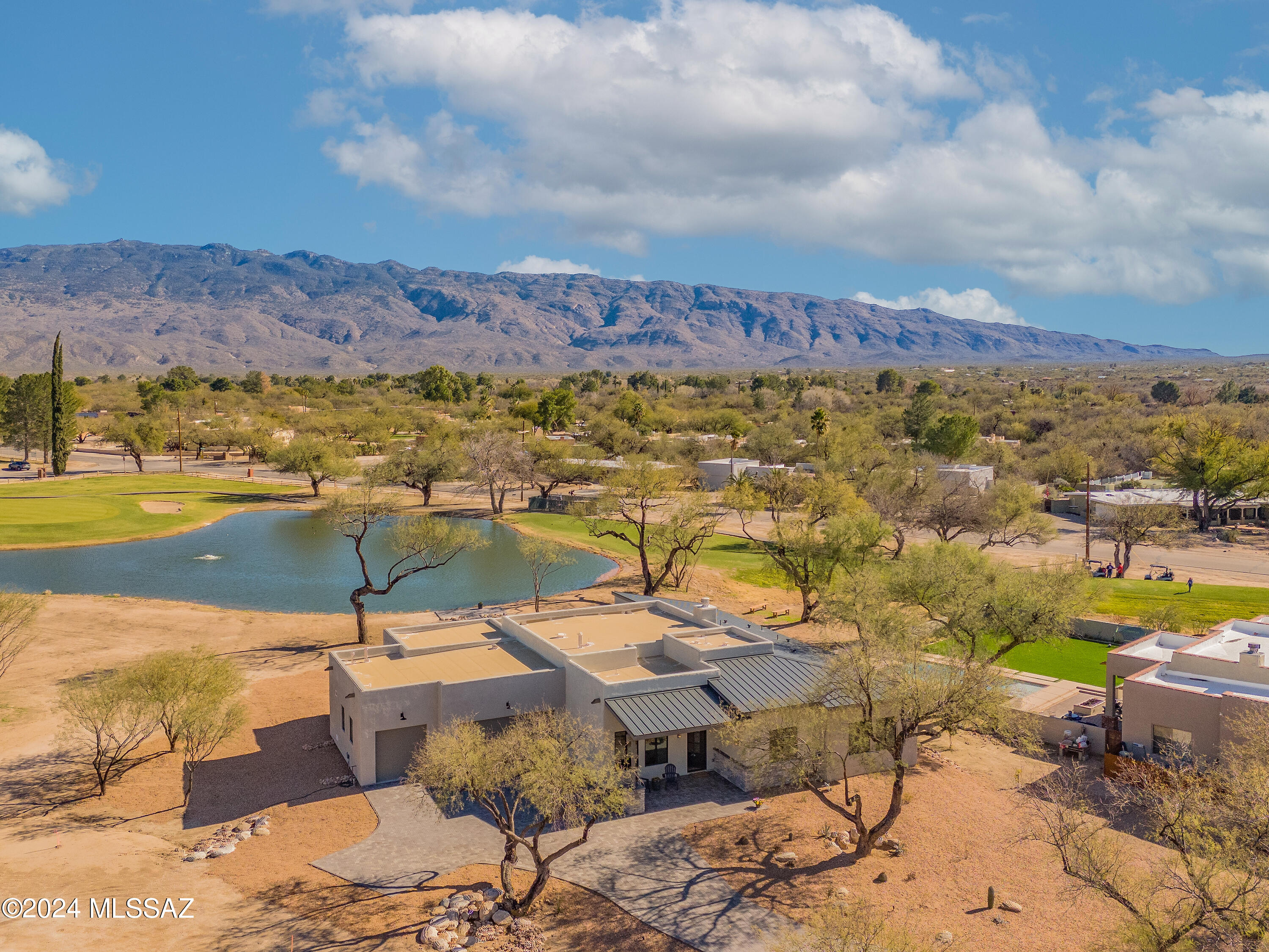 NEW CONSTRUCTION DESIGNER HOME backed up to the lake on Hole 18, over 300 ft of contiguous property line shared with the lake, and Rincon Mountain views! This 3198 sq ft, 4 BR/3.5 BA with office and media room is beautifully situated between mature mesquite trees with large east facing rear patio is ready to move in.  This home has 12 ft ceilings in the kitchen/great room and owner's suite.  Walk to dinner at the country club restaurant, play a round of golf, hit a few balls at the driving range, workout at the fitness center, and enjoy the benefits of living in a well known country club.