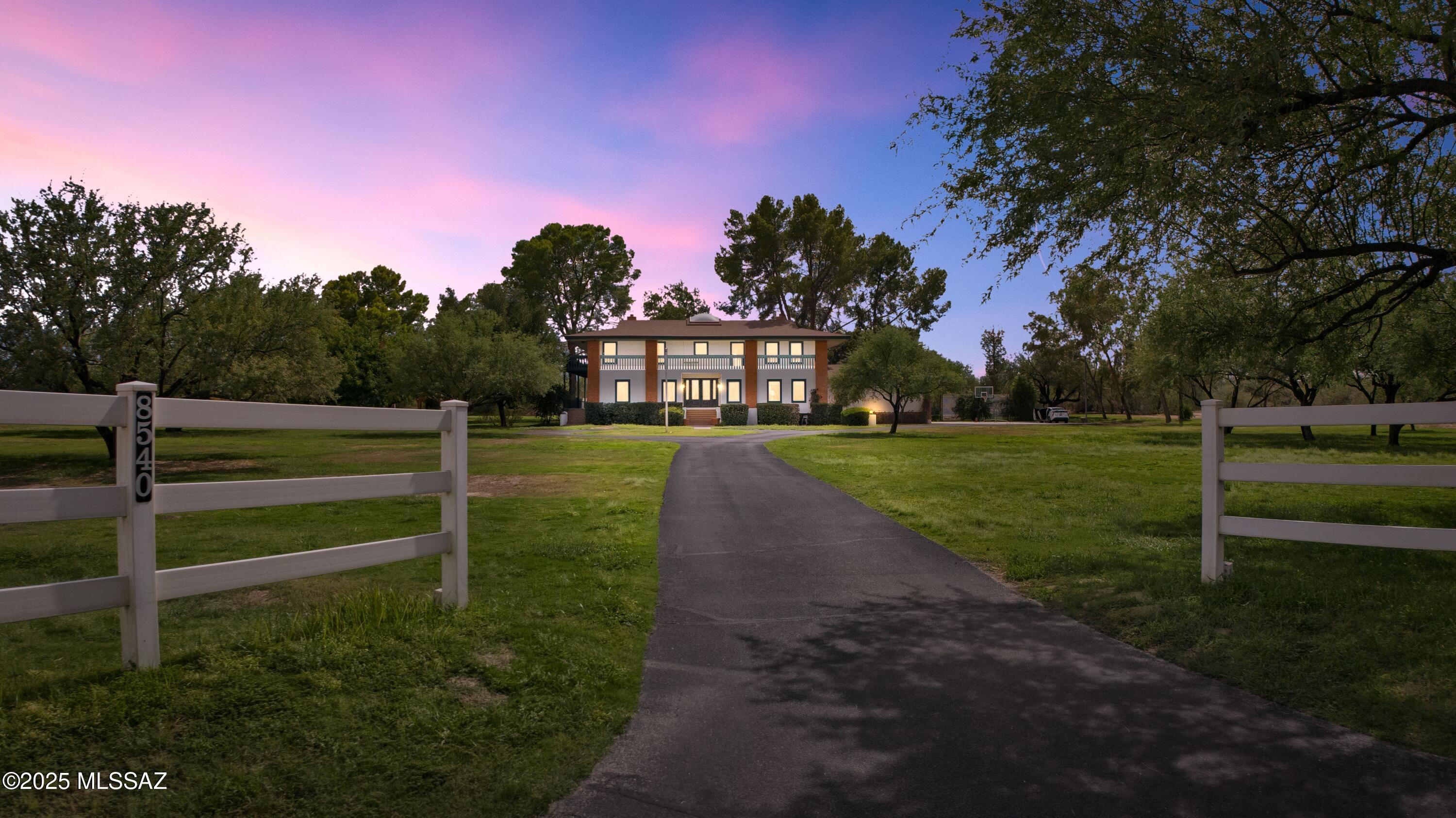 Amazing opportunity to own a truly unique/remodeled home w/guest house & pool in coveted Tanque Verde Country Estates. Arrive via a tree-lined Woodland Rd, down a long/circular driveway, to this warm but stately two story wrapped in porches with sweeping mountain views. The property spans 7.7 horse friendly acres w/private well, grandfathered irrigation rights, direct access to Tanque Verde wash, room for livestock, RV/ rec toys- all with no HOA. Main home offers 5954 sq ft w/a flowing floor plan, six bedrooms (one downstairs) & five bathrooms, high ceilings, maple wood floors, wood beamed ceilings, two double sided sump block fireplaces, immense cabinetry & storage, three car garage. Kitchen features granite countertops, a porcelain stone floor, butcher block island, stainless appliances A covered patio off the dining room and kitchen invites outdoor entertaining, complemented by wraparound porches with stunning views, and spacious lawns. Step outside past the sparking pool to the guest house, a charming 873 sq ft casita with one bedroom, one bathroom, full kitchen, high ceilings & Saltillo tile throughout.  Nearby, a sport court with adjustable basketball hoop offers additional recreation.  This property truly has it all- serene country living just minutes from groceries, restaurants and all the conveniences of town.