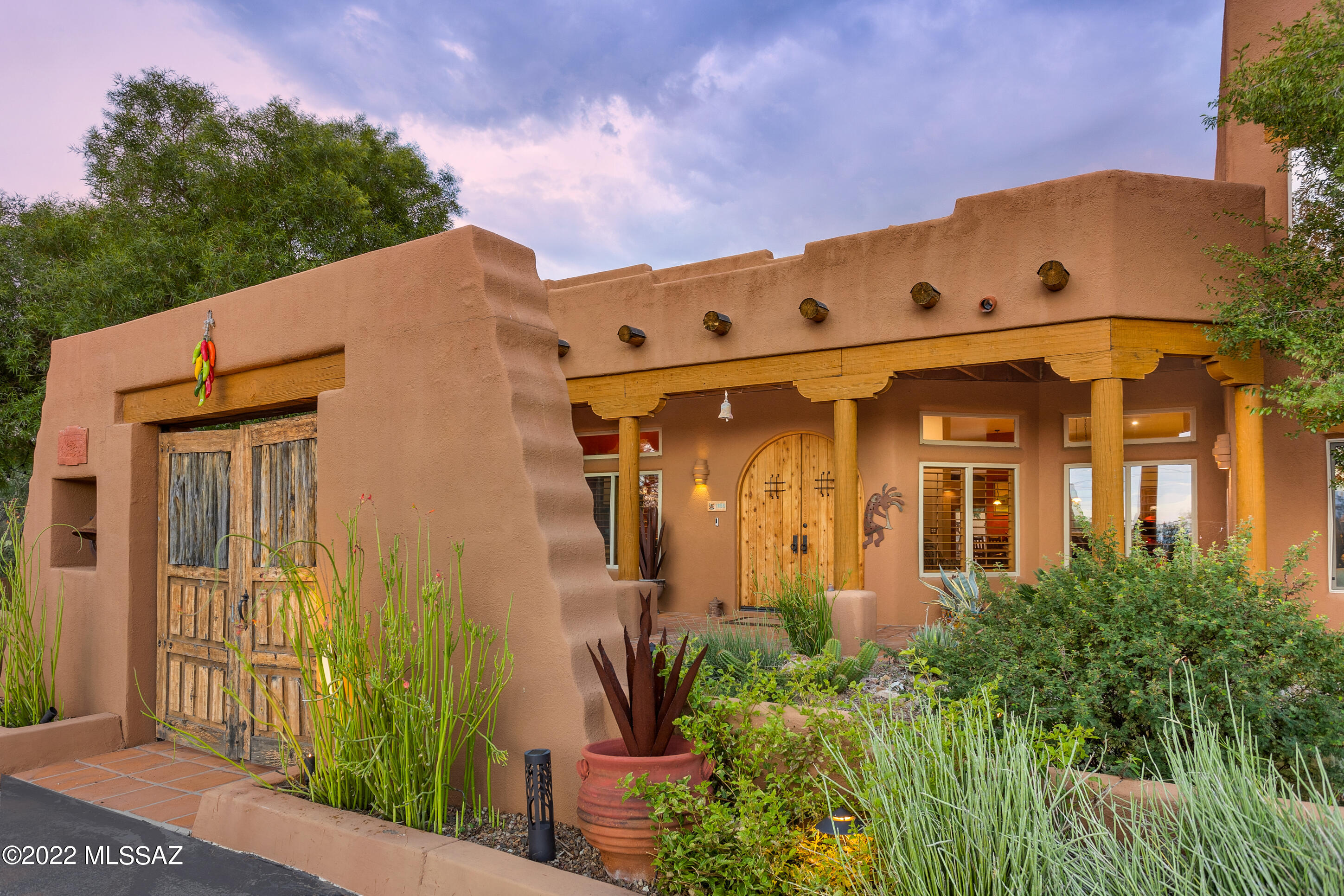 Exceptional Sant Fe on 2.91 acres offers all the charm and amenities you seek. This private gated estate is quintessential Tucson w/ front courtyard, huge covered porches, stained concrete flooring, beehive fireplace, beamed ceilings. The kitchen will please the family chef w/ gas cooktop, built-in refrigerator & wine frig, large breakfast bar. Everyone can have their own space: 5 bedrooms, 4 baths,  library/den, office & craft-room. Spacious primary suite occupies entire 2nd floor w/balcony to enjoy city lights at night. The 4 guest bedrooms share 2 sets of jack n' jill baths. Large yard with sparkling pool, grassy area, pizza-oven overlooks lush desert vegetation and gorgeous sunsets over the Tucson Mountains. Walking distance to Feliz Paseos Park. This home is truly special.