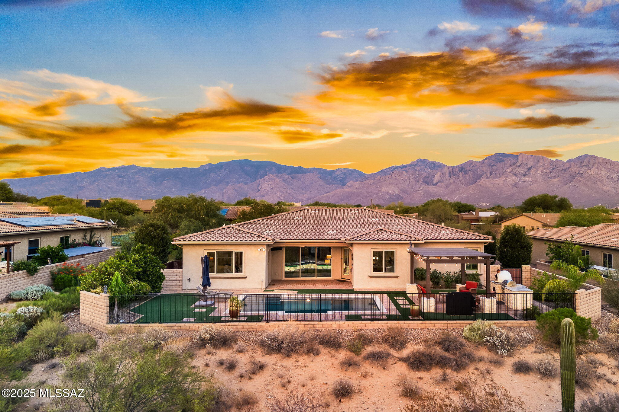 Inside the small, gated community of Rancho Del Colbre in Oro Valley, a turn-key home awaits at 11767 N Luzon Court. This enclave was thoughtfully designed with larger lots for more space & privacy, while maintaining a neighborhood feel. Sitting on a ½ acre, the home backs up to open space, showcasing stunning sunsets and views of both the Tucson & Tortolita Mountains. Many upgraded features were included in the 2015 build, yet the property was enhanced with additional improvements following construction. With 3,526 sq ft, there is ample space to spread out in a well-designed split floor plan that includes 4 bedrooms, 3 ½ bathrooms, and a separate den. High end tile and hardwood floors are found throughout (no carpet). The kitchen is well appointed with upgraded cabinetry that has been extended through the dining area, quartz counters, double ovens, a gas range and stainless hood, plus a spacious walk-in pantry. Ceiling speakers are found both indoors and out.
The backyard has been completed to perfection. A custom designed swimming pool sits adjacent to a covered outdoor kitchen that includes a gas grill, wood fired pizza oven with stacked stone & granite finishes. Thoughtfully balanced turf and paver hardscape blanket the space.  The covered patio includes a television and a motorized retractable awning that nicely increases shaded space when desired.

The 4-car garage is split with a 3-car tandem (main entry) with overhead storage and a separate 1-car bay, that includes wiring for EV charging. All garage spaces have been completed with epoxy flooring. Additional features include a Kinetico water softener and camera system that conveys with the property.
Convenience from this location is plentiful. Within the neighborhood you will find a park with ramadas and a large grassy area. Wilson K-8 School is walkable, and Ironwood Ridge High School 1.4 miles away. Immediately to the south is access to a paved multi-use path that connects to "The Loop." Within 3 miles, you will find the Oro Valley library, Naranja Park, and multiple plazas with grocery, dining, pharmacies, and other services. This location boasts all the benefits of living in Oro Valley, while offering immediate access to La Cholla Blvd, making commuting or traveling Downtown quicker.