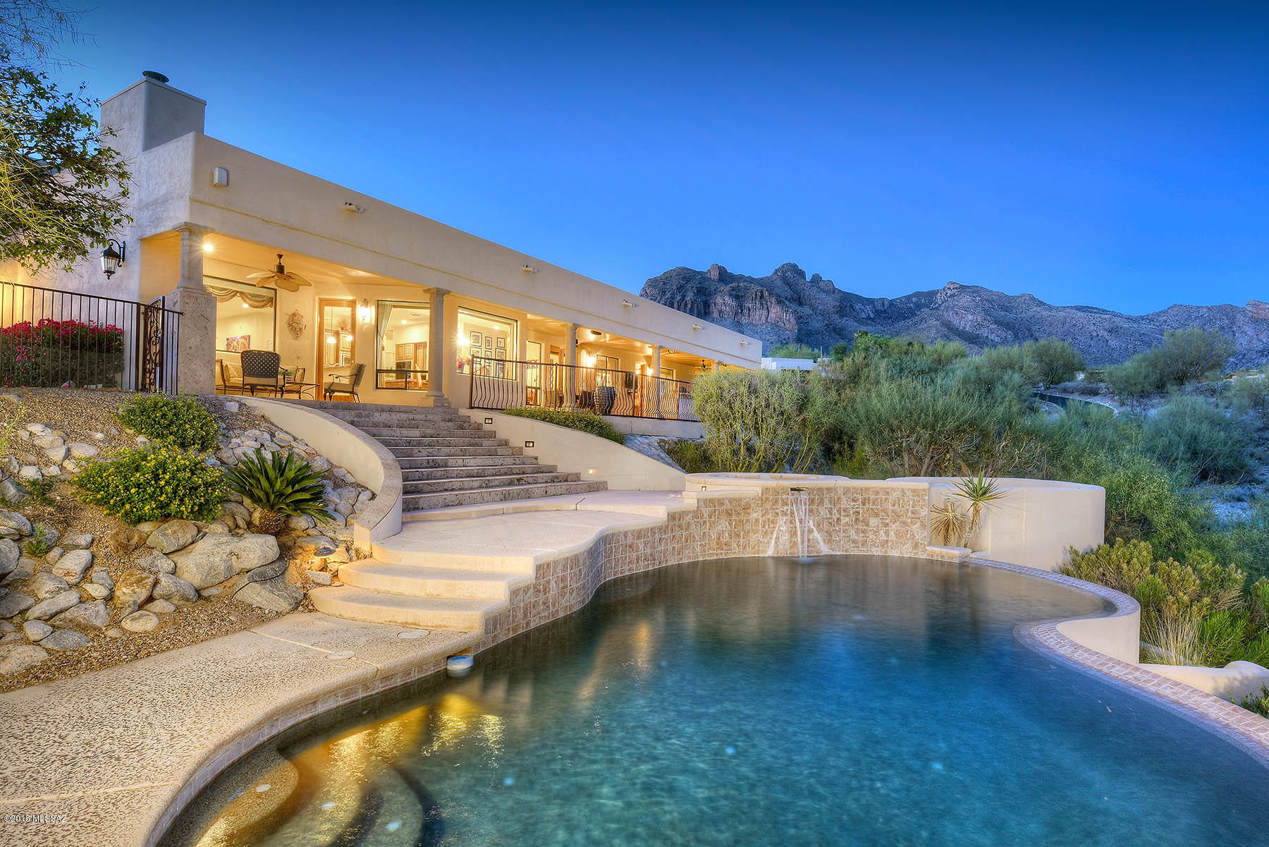 Spectacular city lights & MTN views from this custom hilltop well appointed home. Grand ornamental iron doors welcome you into the spacious foyer. Gourmet kitchen features lux granite, Alder cabinets, double ovens, 5 burner cook top, Sub Zero & eat in area that overlooks the welcoming patio, pool & spa. FR off kitchen boasts cozy cantera FP. Formal LR opens to the intimate patio, large dining room is great for your elaborate entertaining, you can select a nice bottle of wine from your own private wine room. Lavish master suite includes bonus office retreat & work out room, generous mstr ba offers garden tub & vast walk in custom closet. Classy travertine & trendy wood floors thru out. Enjoy Tucson sunsets & city lights on the expansive covered patio with built in BBQ & FP.