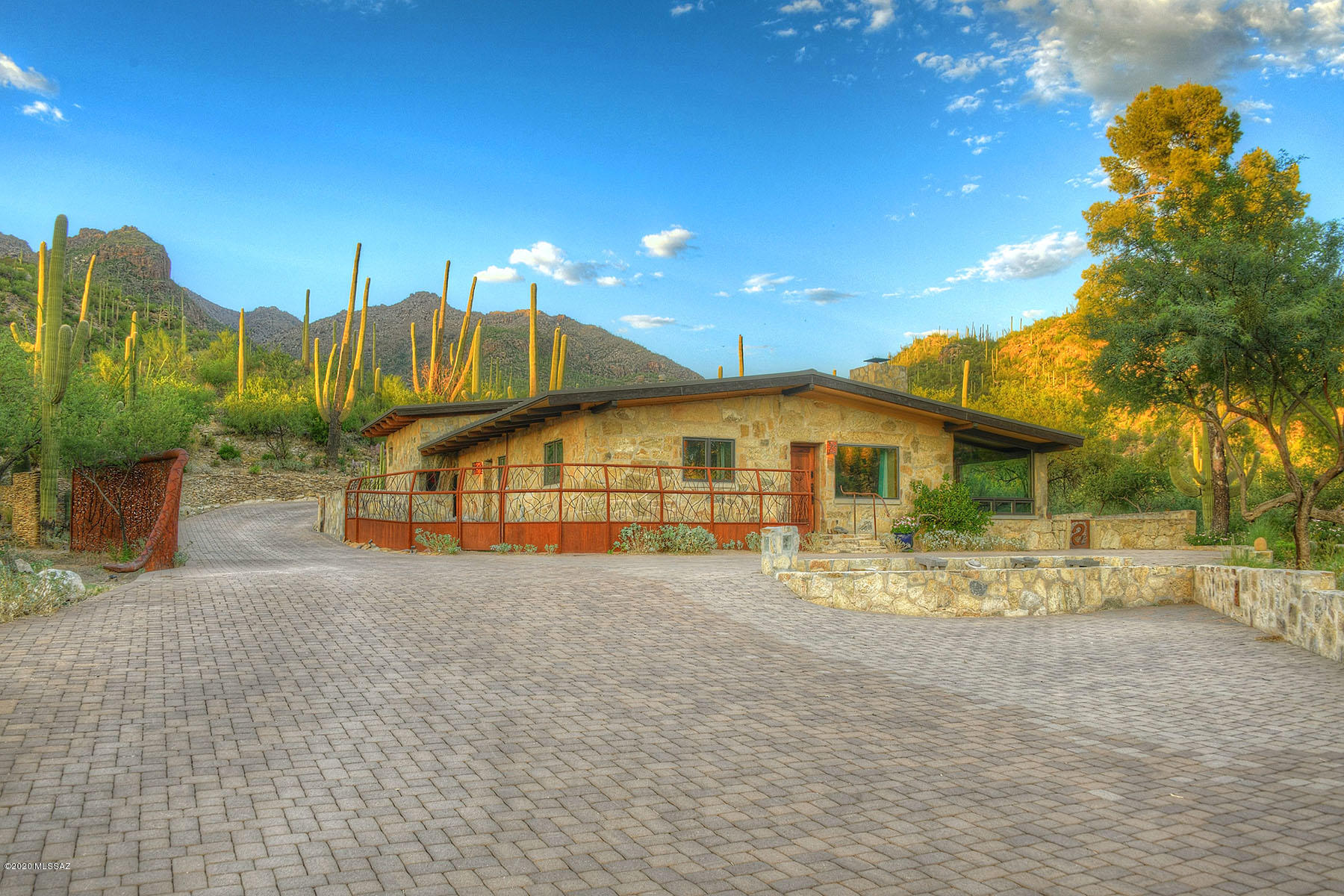Desert living at its finest! Exquisite home on 36 acre parcel which abuts National Forest in the Catalina Mountains. One of the few stone houses remaining & built w/authentic chipped stone from the lot. Many intricate details including hand carved interior doors, stacked stone FP, hand-hewn beamed ceilings, Marvin windows & Mid Century retro kitchen. Living & family room included in this open floor plan. Renovation in 2007 added spacious master w/stone walk-in shower. Detached guest casita & garage extension added in 2012. Amazing 360 views surround acres of natural desert landscaping featuring serene pond, 250 year old saguaros & grinding stones which are scattered around the property. Intimate location situated behind double gates yet close to necessary amenities.