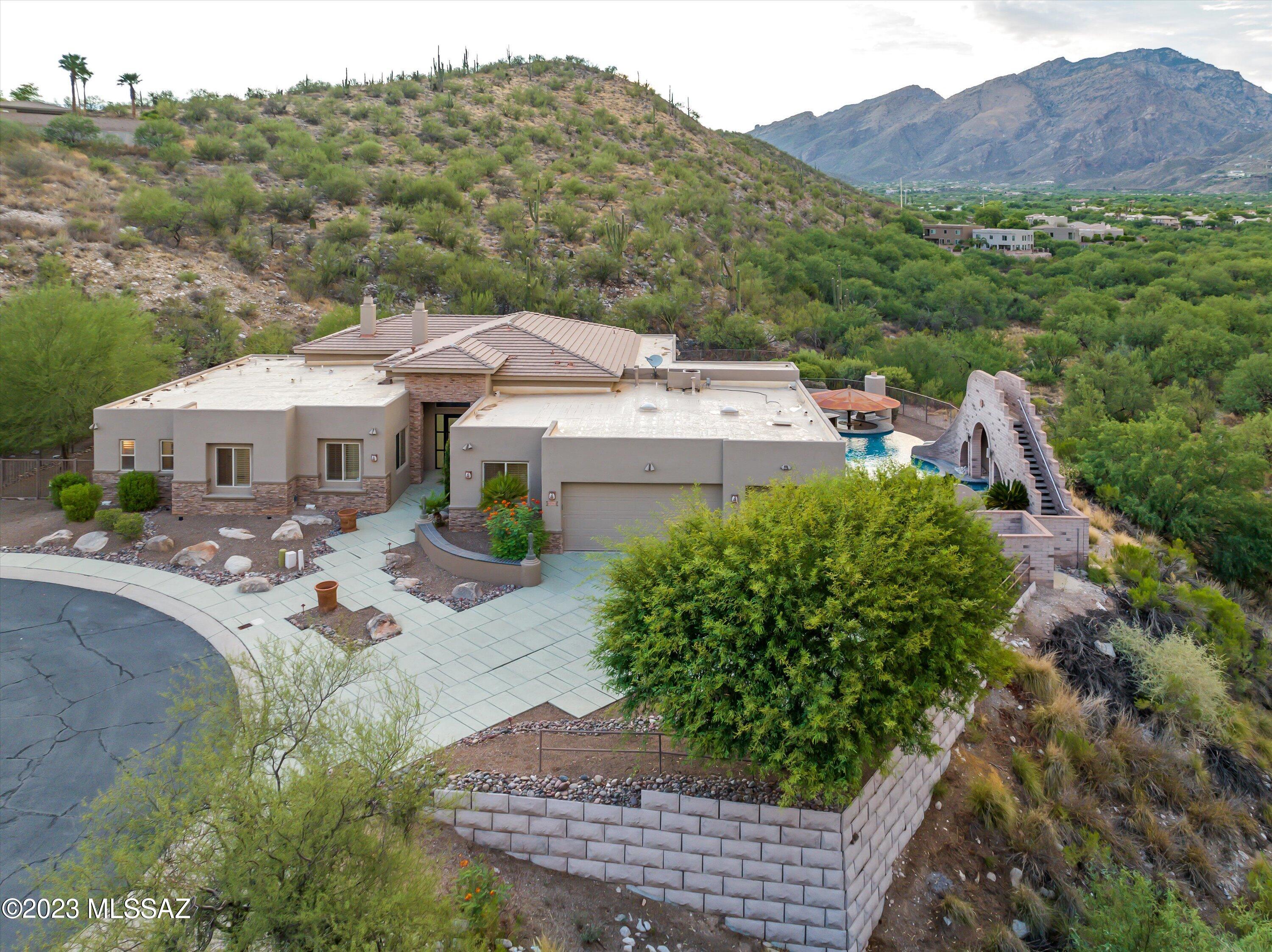 Custom built home on double lot with million dollar views, in a gated community! Inside you will appreciate the 12ft ceilings, the wet bar in the great room, and all bedrooms have their own ensuite. There is a bonus room that would make a great gym or game room along with an office. This kitchen is a chef's dream with a professional grade gas range, large island with wine fridge, so many cabinets for storage & gorgeous granite countertops. The primary suite is all luxury with 2 walk in closets & a private fireplace. Need more space? There is also a separate guest quarters! Step out back & take in the amazing Catalina Mountain view in the infinity edge pool with swim up bar, slide, and spa. The backyard is equipped for entertaining with an outdoor kitchen, covered ramada, & fireplace Welcome to your dream oasis nestled within the prestigious gated community! This custom-built masterpiece sits on a sprawling double lot, offering unparalleled million-dollar views that will leave you in awe. Boasting an exquisite blend of luxury and functionality, this home is a testament to meticulous craftsmanship.

As you step inside, the grandeur of the 12-foot ceilings immediately captures your attention, creating an open and airy ambiance throughout. The great room is a social haven, complete with a sophisticated wet bar that beckons entertaining and relaxation. Each bedroom is a retreat of its own, boasting its own ensuite for ultimate privacy and convenience.

This home offers a multitude of spaces to cater to your lifestyle. Discover a versatile bonus room that could easily transform into a gym, game room, or your personal sanctuary. A dedicated office space ensures that work and productivity seamlessly integrate into your daily routine.

The heart of this home is undoubtedly the chef's kitchen, a culinary enthusiast's haven. Adorned with a professional-grade gas range, the kitchen also features a generously sized island, complete with a wine fridge, offering the perfect setting for both casual dining and lavish gatherings. Abundant cabinet space ensures that all your storage needs are met.

Prepare to be indulged in the lap of luxury within the primary suite. Dual walk-in closets provide ample space for even the most extensive wardrobe, and a private fireplace adds an element of coziness and romance.

For guests seeking their own haven, a separate guest quarters await, providing the utmost comfort and privacy. Stepping into the backyard is like stepping into a resort paradise. The infinity edge pool beckons on hot days, complete with a swim-up bar and a thrilling slide. Immerse yourself in relaxation within the spa as you gaze upon the majestic Catalina Mountain view.

Entertaining is a breeze with an outdoor kitchen and a covered ramada, ensuring that your gatherings are truly unforgettable. And as the sun sets, gather around the outdoor fireplace, creating memories that will last a lifetime.

This home isn't just a residence; it's a lifestyle defined by opulence, tranquility, and endless possibilities. Seize this opportunity to own a property where every detail reflects a commitment to quality and refined living.