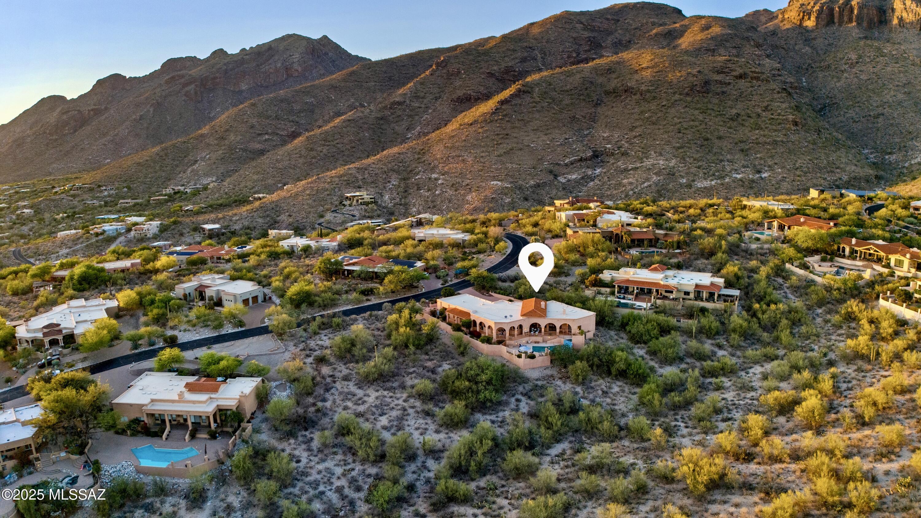 Perched high on a pristine hillside in the exclusive manned-gated community of Sin Vacas, this premier custom home offers an extraordinary living experience in the heart of Tucson's coveted Catalina Foothills. Set on a private 1.533-acre lot, this property blends natural desert beauty with sweeping, infinite views that stretch across Tucson's skyline—from the twinkling city lights and iconic A-Mountain to the majestic Santa Ritas and the rugged Tucson Mountains. This timeless residence, masterfully crafted and lovingly maintained by its original owners, showcases refined architectural design that gracefully echoes Mediterranean, European, Spanish Colonial, and Southwest influences. A serene courtyard welcomes you into the home, where every window reveals panoramic mountain vistas and cityscape views.

Thoughtfully designed for both grand entertaining and intimate relaxation, the expansive wrap-around covered patio invites seamless indoor-outdoor living, with walk-outs from all living areas. Terraced patios and a graceful sidewalk ramp lead to the stunning heated infinity-edge swimming pool with a Pebble Tec finish waterfall from the elevated spa. The built-in BBQ and serving area is perfect for al fresco dining under Arizona's vivid skies. The preferred north/south orientation captures sunrises and sunsets with unmatched clarity, while the professionally landscaped grounds and artisan-crafted lighting add warmth and elegance to the outdoor experience.

Inside, cathedral ceilings greet you in the foyer, giving way to spacious, sun-filled living areas. The elegant living room, complete with a floor-to-ceiling gas fireplace and dry bar, opens into a thoughtfully appointed kitchen featuring deep drawer cabinetry, double wall ovens, a warming drawer, and intricate tile inlays.

The split floor plan features two luxurious primary suites, each with a sitting area, customized walk-in closets, spa-inspired en-suite baths, and private access to covered patios. This layout graciously accommodates multi-generational living or dedicated guest quarters. Additional rooms accommodate bedroom use, office, recreation, or creative space. A sunken wet bar in the family room, a large laundry room with a sink and granite folding counter, and a key-drop station enhance the home's functional sophistication.

The oversized finished three-car garage impresses with a new "Granite Finish" floor under a lifetime warranty, built-in cabinetry, refrigerator, upright freezer, and leads to the dedicated workshop which is a hobbyist's haven. Dual sets of French doors provide easy access and effortless movement of tools and equipment. A separate service door opens directly to the backyard. The layout offers functionality for both storage and seamless workflow.

The large circular driveway provides ample parking for numerous vehicles.  The drive, as well as the patios, are integral-colored concrete for a long-standing upscale finish.

This residence has been impeccably maintained with recent updates to include zoned HVAC systems with new units installed in 2020 and 2024, newer windows in key rooms, a well-maintained roof with recent coatings, Pebble Tec pool finish in 2020, a new pool light, thermostat, and pressure switch in 2025.

A rare blend of serenity, architectural style, and scenic grandeurmake this remarkable Sin Vacas residence more than just a home; it's a timeless expression of inspired desert living.
