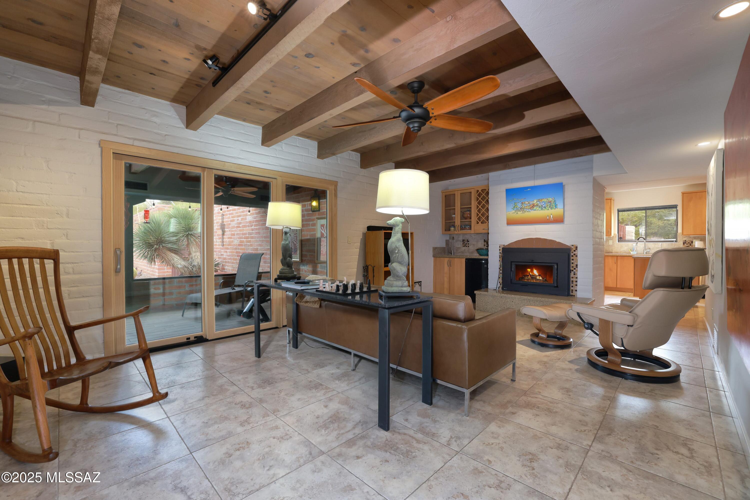 Discover this beautiful territorial home in the heart of the Foothills! The large front porch welcomes you into the family room w/big south facing windows for city views and on to the formal living room boasting gorgeous wood ceilings, cozy FP & built-in bar, ideal for gatherings. Chef's kitchen offers warm maple cabinets, SS appliances & sleek granite counters. You'll find lovely neutral tile throughout with new wood floors in the bedrooms. Generous primary suite features an updated bath & a large walk-in closet. Spacious AZ room provides a great setting for year-round outdoor entertaining. Step outside to your own desert oasis w/a sparkling pool & views of the saguaro-studded landscape. With a 2-car garage & a prime location near shopping & dining, this is Tucson living at its finest.