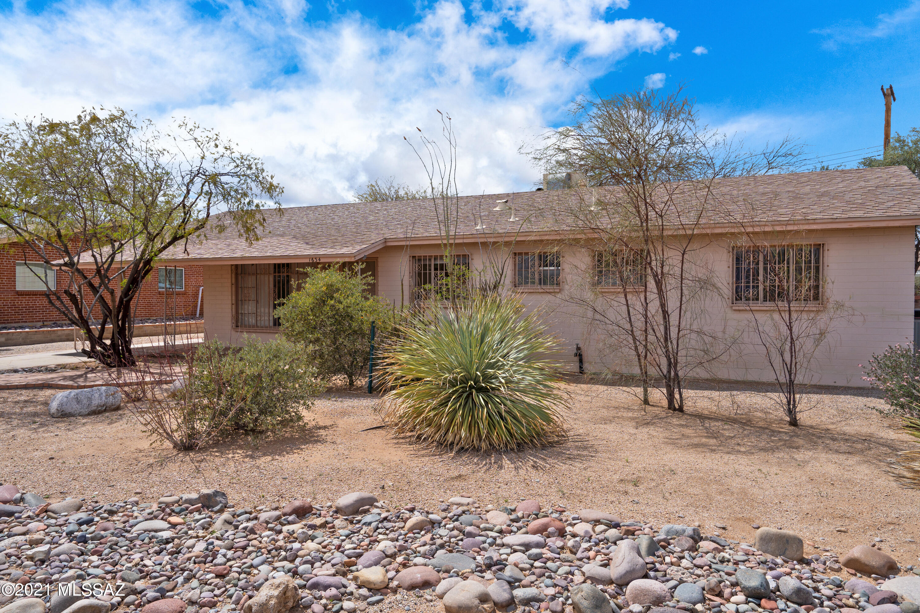 Fantastic opportunity to own in Terra Del Sol neighborhood. Three bedroom, two bathroom home with additional storage space and single carport. Lot is very desirable with mature vegetation, beautiful brick patios, and surrounded by a masonry wall. Kitchen has charming tile details, breakfast bar, and large window. Generously sized spaces indoors and out.