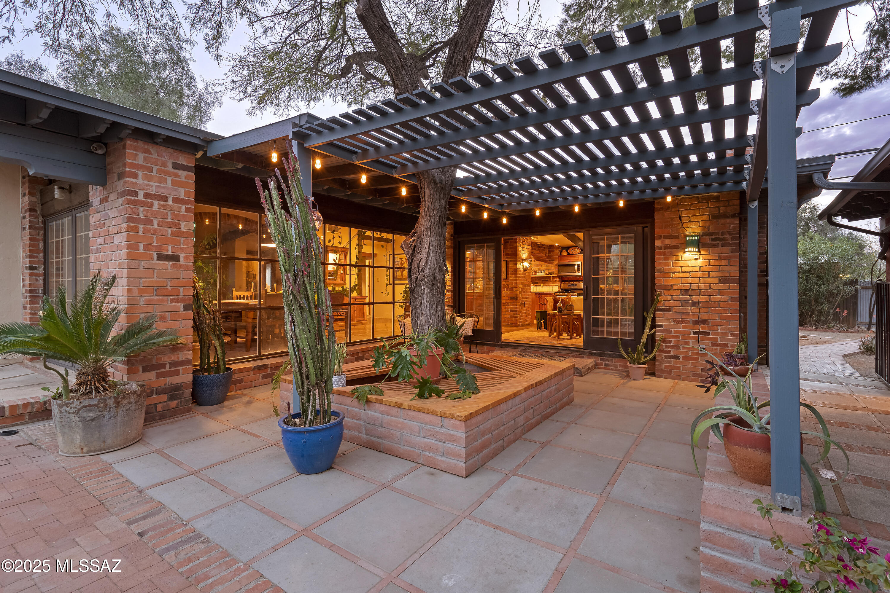Located in the heart of central Tucson, this stunning ranch-style burnt adobe home offers the feel of a private retreat while keeping you close to everything Tucson has to offer. Brick arches, exposed wood beams, and Saltillo tile floors exude warmth and authentic Sonoran desert charm, while thoughtful updates and solar panels add modern comfort.

The main house features an open split floor plan with generous living spaces. Large windows and sliding patio doors fill the home with natural light and create a seamless indoor-outdoor connection. The primary suite includes a spa-like bathroom, new walk-in closet, and a versatile nook—ideal for a home office, yoga space, or reading retreat.

The detached casita offers exceptional privacy with its own driveway, entrance, and secluded patio. French doors open to a spacious living area and naturally-lit kitchen, while a flexible bedroom layout makes it perfect for multi-generational living or rental potential.

Step outside to a fully fenced, oversized lot with mature desert landscaping and large trees. Multiple patios, shaded pergolas, and garden-ready spaces provide privacy, tranquility, and room to create your own outdoor oasis. Abundant parking and a covered carport add convenience and functionality.

A rare opportunity to own a unique, beautifully maintained home in a prime location. This rustic midcentury home is just a short distance to the Mountain Ave. bike path, the University of Arizona, and Banner Hospital.