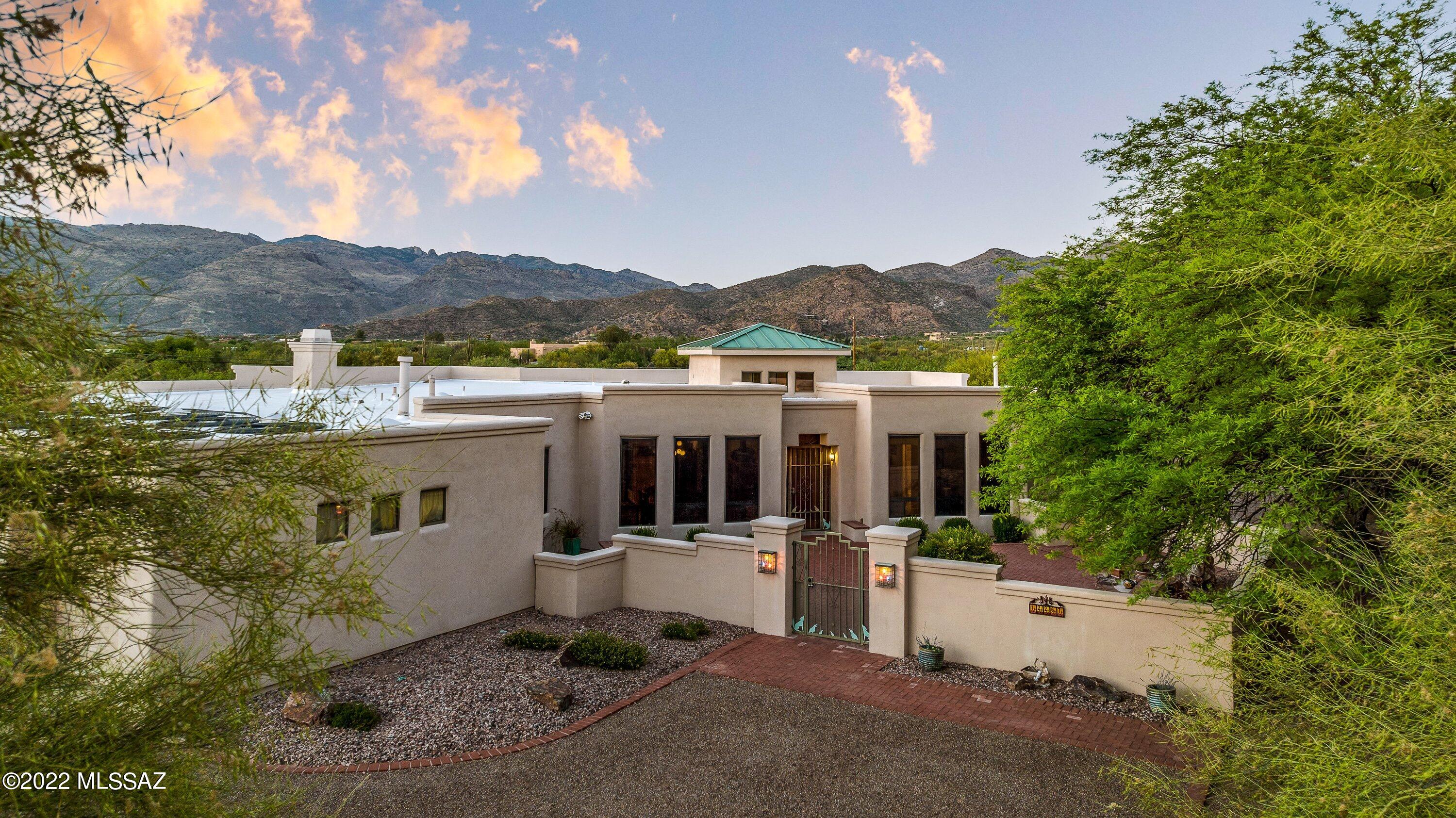 Stunning SW Contemporary home boasts panoramic mountain views. Nestled on nearly an acre of mesquite trees and mature landscape on quiet cul de sac. Paver courtyard entry welcome you to this 5BR,4BA split floor plan design with soaring ceilings, polished concrete flooring and expansive windows throughout that brings the outdoor living in. Gourmet kitchen with 5x7 island granite island, prep sink, Dacor double ovens and gas cook top range opens to family room with fireplace and lovely breakfast nook. This desert oasis offers tantalizing pool with gas heater & solar coils. Pull up a lounge chair a relax under the covered patio or by the kiva fireplace to be captivated by the majestic mountain views. An entertainers delight in this private backyard with putting green. AC & water heater is new