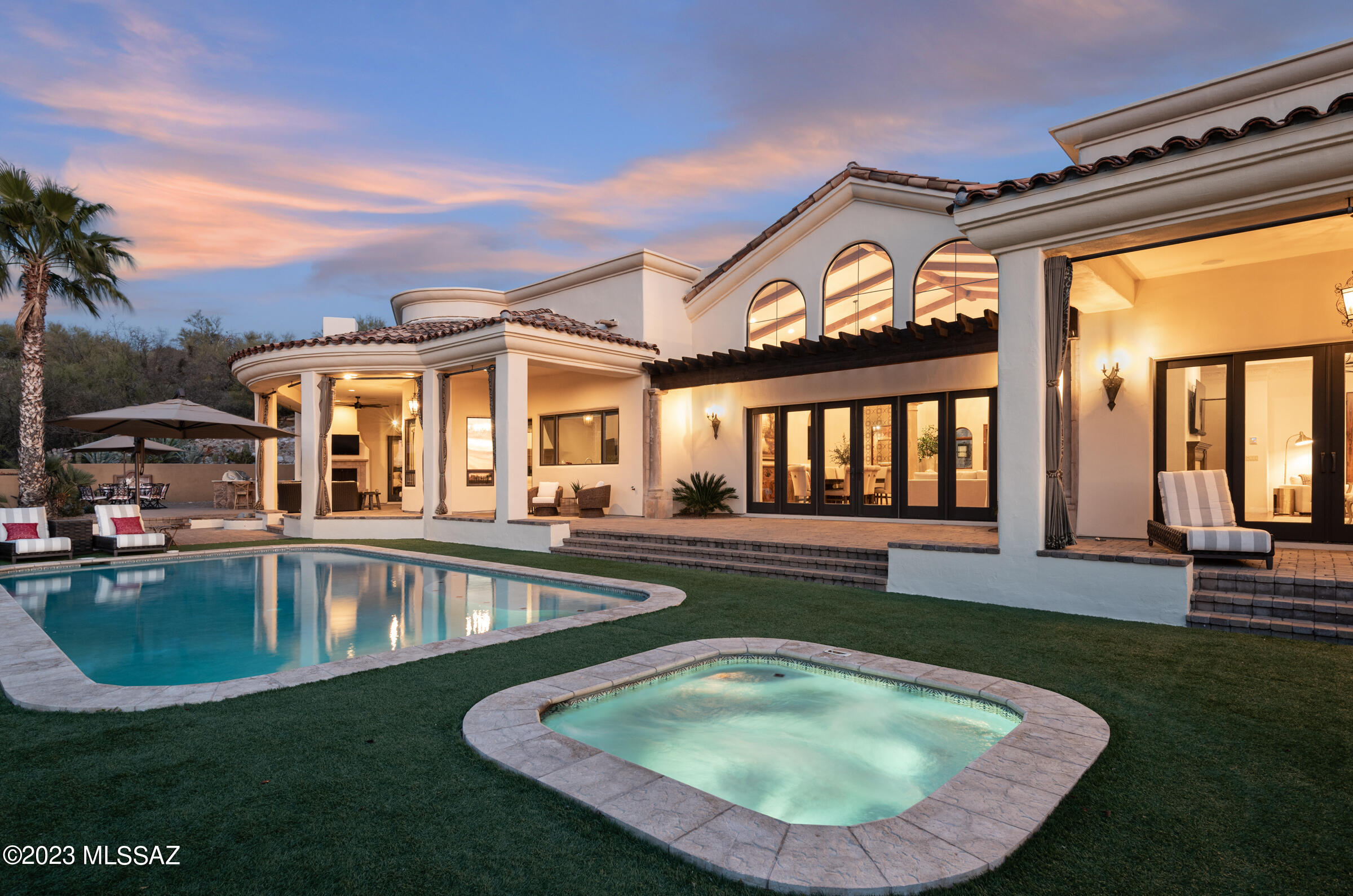 Situated on an elevated near one-acre lot, this exquisite 2006 foothills home is perfectly sited to capture the entire expanse of breathtaking Catalina Mountain views. All you need to do is absolutely nothing to move into this Mediterranean masterpiece located in a small, gated enclave of custom homes near Ventana Canyon. This sprawling, five-bedroom residence has a masterful design & thoughtful layout that spares no detail for enhancing both entertaining guests & everyday living. The 5900 sf main level is  without any steps, the stairs that lead down to a separate 900 sf living quarters w/ private entrance, kitchenette, large living area & bed & bath are the only steps in the house. Everything you need to live in this exceptional home is on the main floor, downstairs is a bonus area. The ever-present quality and attention to detail give way to an experience that merges the spellbinding beauty of the Sonoran Desert with the feeling of a hillside European Villa.  Enter through an impressive foyer that leads to the great room with a massive wall of windows that showcases the unobstructed mountain views to the north. This magnificent room with a formal dining area has soaring 21' foot wood beamed ceilings, decorative hand-made wrought iron panels, a grand fireplace covered in antique-colored concrete, and hand-carved hardwood plank floors. An exquisite library with custom built-in shelving creates an interesting use of space off of the great room. A temperature controlled 750 bottle wine room and a powder room for guests create the ultimate space for entertaining. The island in the kitchen is the centerpiece of this dream kitchen, outfitted with Sub-Zero, Wolf, and Miele appliances, custom cabinets, tile backsplash, and large windows that frame the mountains & pour in natural light. The kitchen is open to the family room with a gas fireplace, informal dining area, and distinctive Italian-fired Terra Cotta Flooring.  Butler's pantry with sink connects the formal dining area in the great room to the kitchen area.  The master suite occupies the west wing of the home features a large bedroom with a gas fireplace and his and hers master bathrooms, hers with a separate shower, a claw foot tub with incredible mountain views, and new storage cabinets, and a large walk-in closet. His bathroom has a steam shower and a walk-in closet.  Three ample-sized en-suite bedrooms occupy the east wing of the home, with a unifying bonus area that is a perfect playroom for kids or a place to hang out and watch TV. Outside is a true oasis with a heated pool and a spa with all new equipment that is surrounded by low-care turf. Patios lined with pavers provide multiple spaces to take in the glory of the mountains, beautiful sunrise or sunset, or watch the twinkling lights at night. A casual space under the covered patio is an outdoor living room with a gas fireplace and television. It is located next to the outdoor kitchen with a built-in Lynx BBQ, sink, refrigerator, and new countertops. Huge laundry room with large sink, extra refrigerator, tons of storage cabinets, and desk area. Spacious 3-car garage with storage area, built-in cabinets, and work area. 
Newer 17 seer HVAC Equipment, Entire Exterior of home and surrounding walls painted March 2023, new pool pump and filter in 2021, new counters at outdoor kitchen, current owner added storage cabinets and counter in "her" side of the master bath
This home is located in District #16 Schools, including Ventana Vista Elementary School, with the Spanish Immersion program. Basis Charter School and the Gregory School are nearby. You can walk to some of the best restaurants and shops Tucson has to offer, and it's just moments from the Ventana Canyon Country Club and Golf Resort and the Sabino Canyon recreational area.