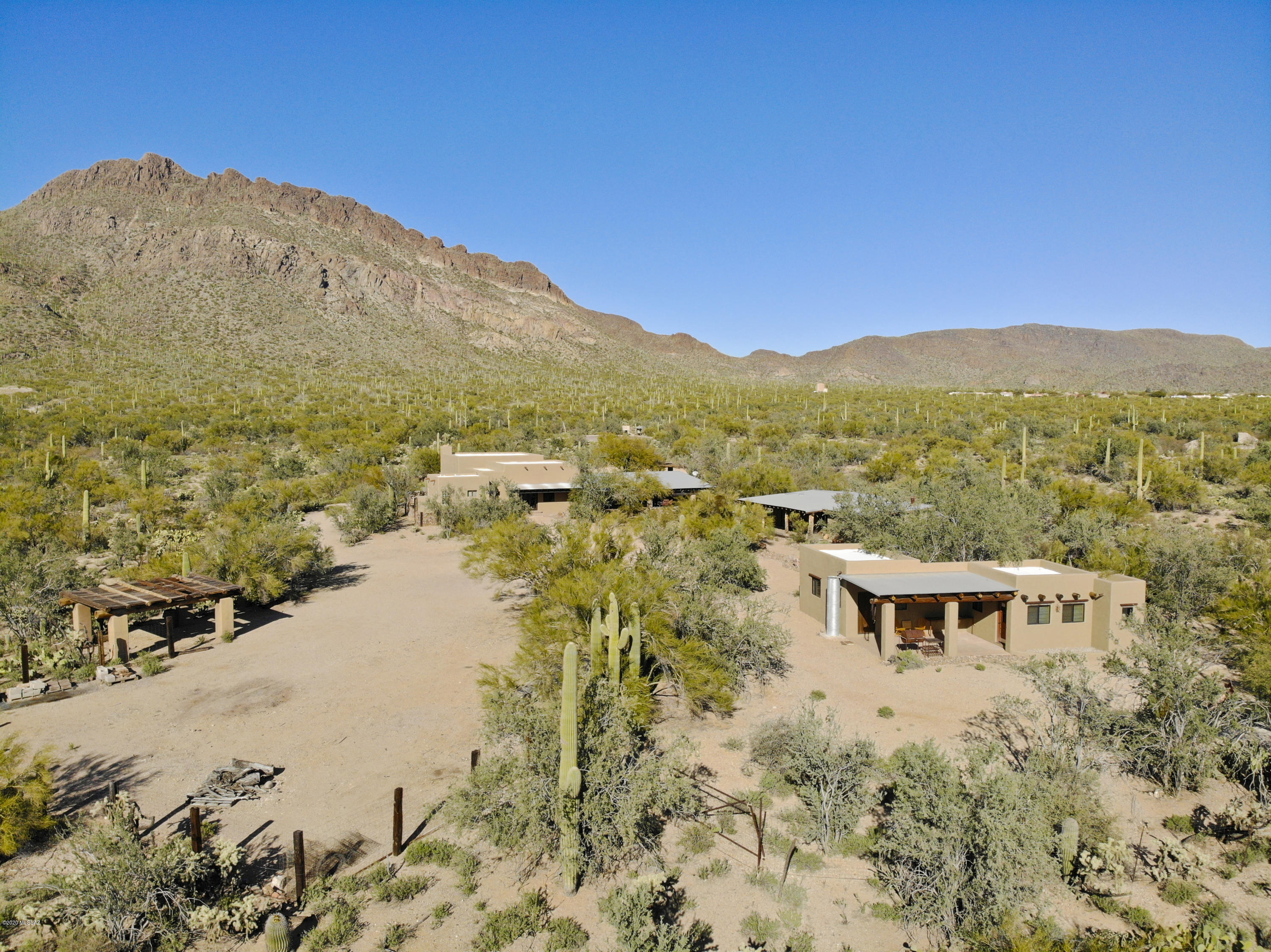 Southwest living doesn't get better than this one-of-a kind gated ranch property totaling 8 acres backing up directly to Tucson Mountain Park. Pictures can't do this property justice! Feel like you're living on a movie set with a luxuriously updated 3,200 sq. ft. main home looking at the gorgeous Tucson Mountains & featuring concrete, wood, & tile floors, soaring beamed ceilings, modern kitchen finishes, and unique territorial touches; a guest house with a full kitchen & living space; plus a ''bunk house'' studio with en suite bathroom. The property has endless possibilities as a full-time residence, bed & breakfast, or corporate retreat. The outdoor BBQ & patio spaces are truly a standout feature, and the main courtyard area could accommodate a pool or large events. Character galore!