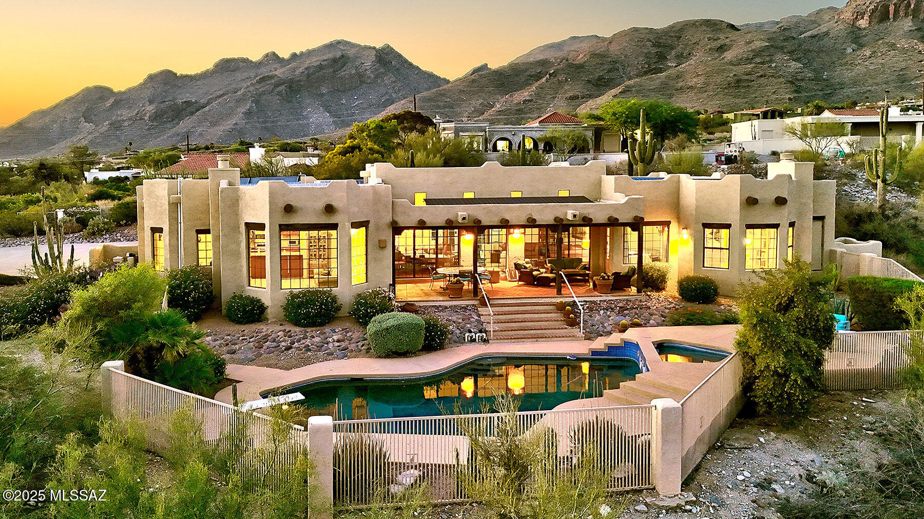 Step through the gated entry courtyard into an inviting interior filled with natural light. A combination living/dining room with beautiful views of the city and surrounding mountains, a warm family room with a fireplace and a well-appointed kitchen with generous counter space and cabinetry.
Retreat to the private primary suite with its own sitting area and fireplace, Japanese soaking tub, and direct access to outdoor living.  (Research shows that immersing oneself in hot water up to the shoulders before bed can encourage drowsiness.)Three additional bedrooms..
Outdoors, enjoy phenomenal views of surrounding mountains and expansive city lights from your private pool and patio.  Walkable to La Encantada. Located a the top of a hill at the end of a cul de sac. Solar panels owned