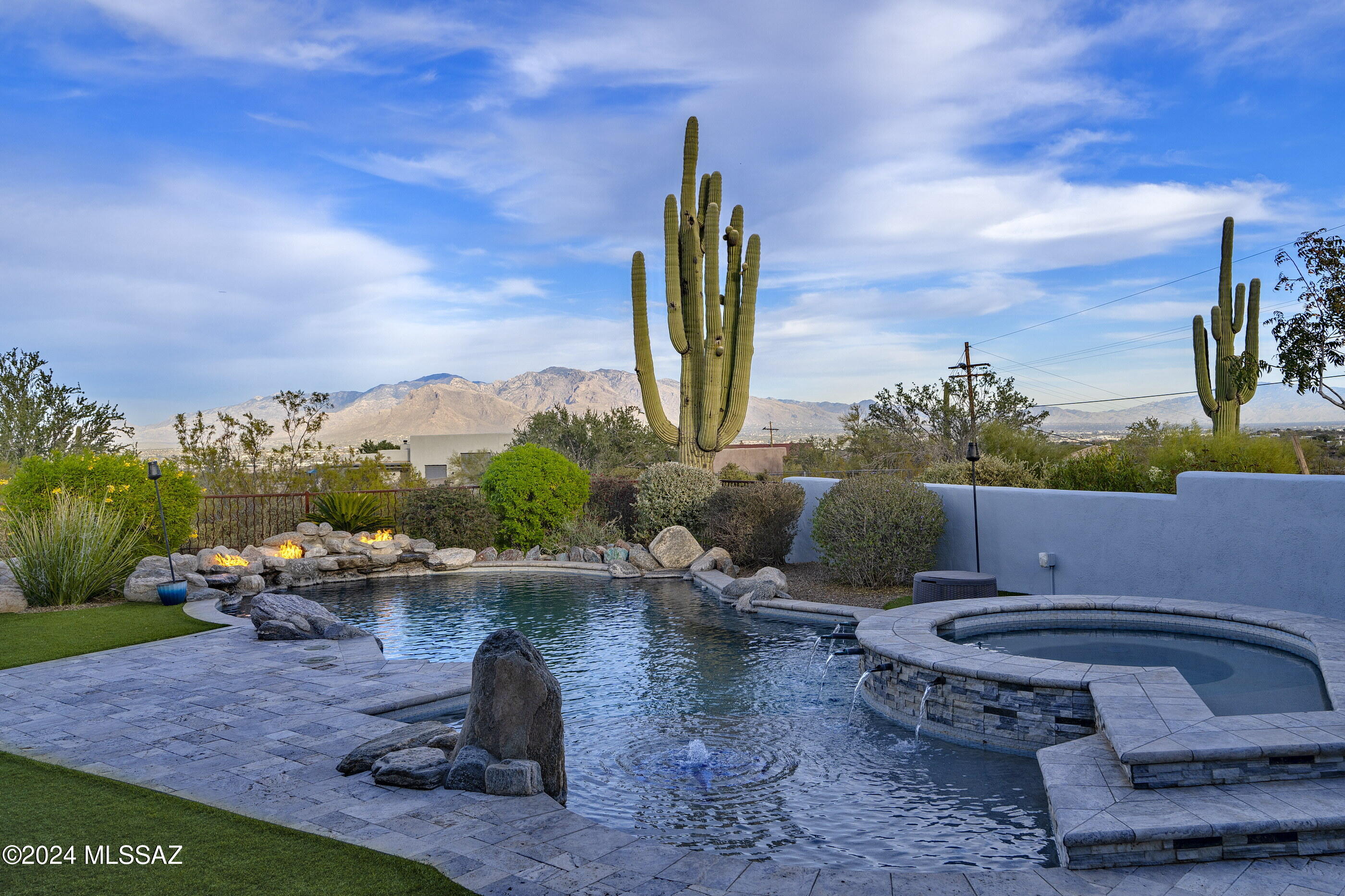 Home sits on 4+ acres of hillside high desert nestled between Saguaro National Monument West & Tucson Mountain Park boasting of panoramic city & mountain views! A backyard oasis features a large covered patio, fenced yard, & breathtaking custom pool w/large lagoon, waterfall features, fire pits, & spa, w/dual heating via propane or solar.  Among upgrades: PAID OFF SOLAR! Gutters & water retention tanks (2023), NEW HVAC (2023), Pool Equipment Upgrade (2023), Pool (2017), NEW IRRIGATION (2023), REMODELED KITCHEN(2024), NEW HOT WATER HEATER (2024), NEW INTERIOR/EXTERIOR PAINT(2024).Newer kitchen appliances (2023) & washer/dryer (2022) convey w/home and that's not all..new carpet (2024), shade trees added (2024), pool solar (2019). Private/Serene Setting. Courtyard entry invites you into a huge great room w/soaring ceiling, corner slate wood burning fire place, 20" porcelain tile, Split bedroom floor plan.  Guest suite has private bath. Oversized 3 car garage.  City water! Unique hillside lot.  Shared road agreement.  See all attachments to this listing.