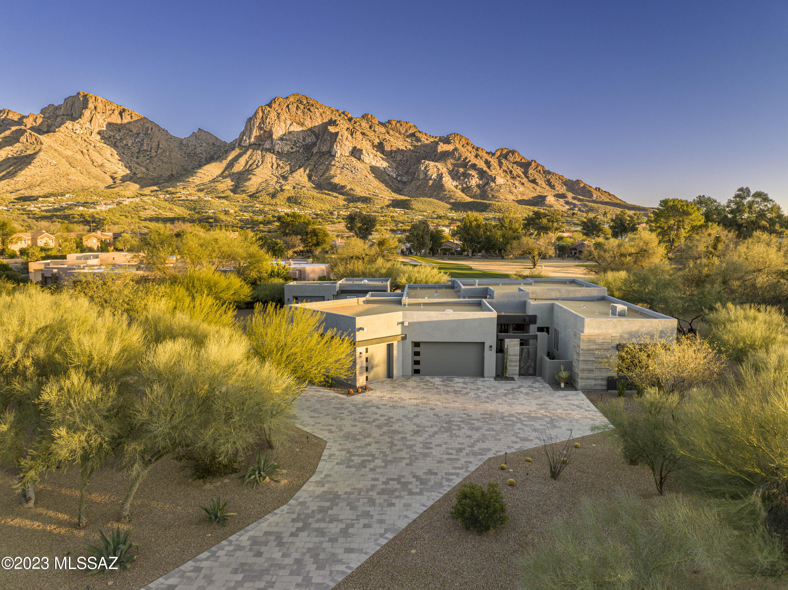 This gorgeous modern estate has arguably the best views in all of prestigious Oro Valley Country Club. Set on 1 acre of tranquil grounds this home includes stunning mountain and golf course views through the giant wall of windows.  The precise landscaping has perimeter hedges, contemporary travertine walkways and terraces that allow for great entertaining and outdoor enjoyment. In addition this home boasts an oversized three car garage with 500 square feet of heated and cooled flex space not included in the listed square footage. Other amenities include high ceilings, motorized shades, workshop/golf car garages, built in bar, gas fireplace, security system, newly constructed SwimSpa with solar, citrus trees, circular driveway and a private iron door entry. Come enjoy the good life!