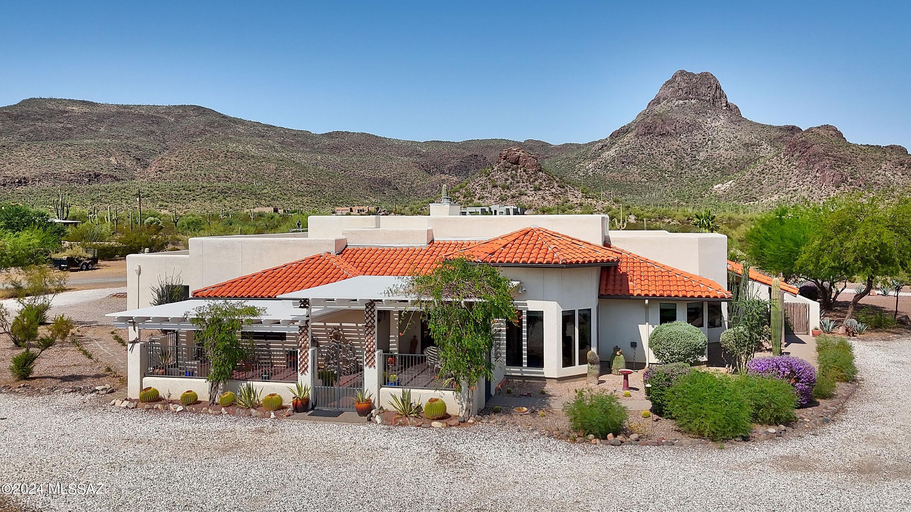 Your tranquil desert oasis awaits w/stunning mountain views out the front & back. Luxurious interior and spacious split plan on an expansive 3.37 acre lot features an incredible wkshp w/parking for all your toys. The sizable front courtyard w/bancos sets the stage & the living areas offer soaring ceilings & lg windows facing directly at Sombrero Peak. Dining rm is a showstopper w/amazing wood ceiling & wall of windows. Gourmet kitchen features rich cabs, superb granite & SS appl. Open design flows into the family & living rms w/stunning 2-sided FP.  Huge primary w/dual vanities, soaking tub, sep shower & W/I closet. Sparkling Pebble Tec pool, trickling fountain, lush landscaping & patio.   3-C Gar + 5-C Carport/RV Spots makes this the ideal property for the hobbyists & horse enthusiasts.