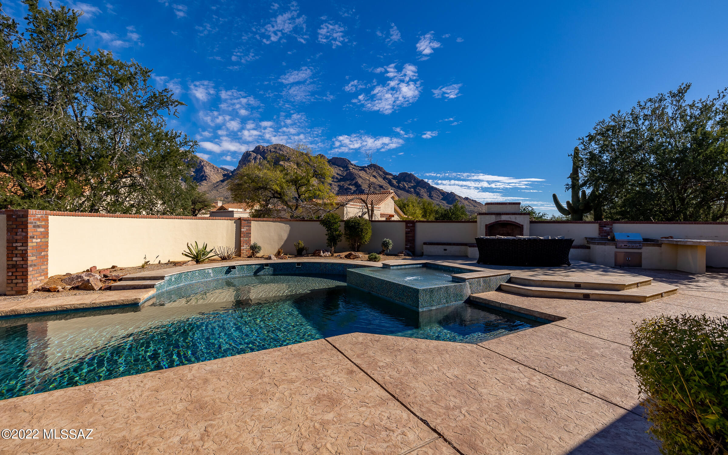 As you enter this beautifully walled property you are immediately engulfed by this warm, welcoming home set against the backdrop of spectacular Pusch Ridge and western slopes of the Catalina Mountains. As you gaze at the views in front of you it is easy to forget you are minutes away from Oro Valley Country Club and all of its amenities, as well as some of the finest shopping areas in all of Tucson. Relax under the wrap around covered patio or in the salt water pool and spa. Retire to the huge owner's suite with a closet and bath your friends will envy. There are three large auxiliary bedrooms and two more full bathrooms. The flex/family room shares a double-sided fireplace with the kitchen/dining area.  Solar system is fully owned.
