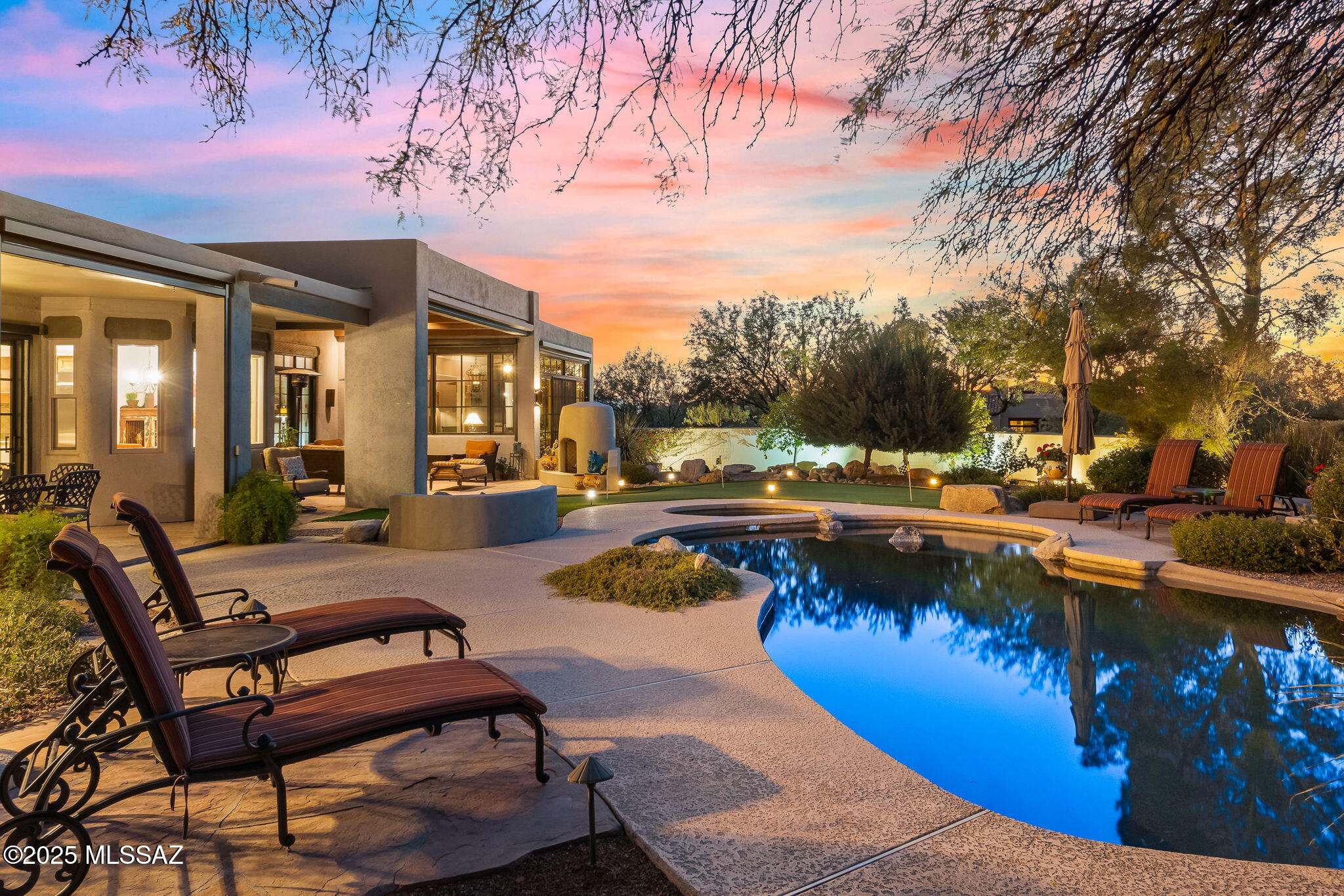Welcome to impeccably designed & beautifully appointed foothills home in the exclusive gated community of Canyon View Estates. This 3395 sq. ft., 4-bed, 3-bath property sits on 1.11 acres & has so much to offer. Entrance creates a memorable first impression w/stunning gated courtyard adorned w/flagstone, vibrant bougainvillea & mission-inspired architecture. Step inside through custom metal & glass doors to a thoughtfully designed home where bedrooms & living spaces flow around the courtyard, creating a unique blend of openness & intimacy. The living room is a showstopper, featuring wood beams, a wood-clad ceiling, Saltillo tile floors, a gas fireplace & wood French doors that lead to the beautifully landscaped backyard. The formal dining area boasts courtyard views. Chef's kitchen MORE is an entertainer's dream, offering a mix of quartz & granite countertops, an antibacterial sink + premium appliances. Lovely breakfast nook offers views of scenery of lush backyard. Kitchen opens to breakfast nook, family room & boasts tons of prep space & storage. Family room with custom solid wood entertainment center & beehive fireplace. Two sets of French doors open to the backyard, blending indoor & outdoor living seamlessly. Primary suite is a stunning, tranquil retreat, offering a spacious bedroom filled with natural light, gorgeous fireplace & lots of space. Off the primary suite, a beautiful, solarium-style den w/stunning views of the Catalinas is the perfect space to relax. Split bedroom plan. Guest suite features bathroom w/a walk-in shower while 2 additional bedrooms & another spa-like full bath w/double vanity ensures optimum functionality. Backyard is entertainer's paradise, complete with a Pebble Tec pool & spa, putting green, built-in BBQ, beehive fireplace & several seating areas. Motorized shade screens & ample lighting make outdoor living comfortable year-round. Large laundry room w/folding area, beverage cooler + storage. An XL 3-car over-height garage with huge storage room. Home is the perfect combination of comfort, luxury, & location. Don't miss the opportunity to make this incredible property your own! Close to schools, recreation, Sabino Canyon, shopping & restaurants. District 16 schools. Welcome home!