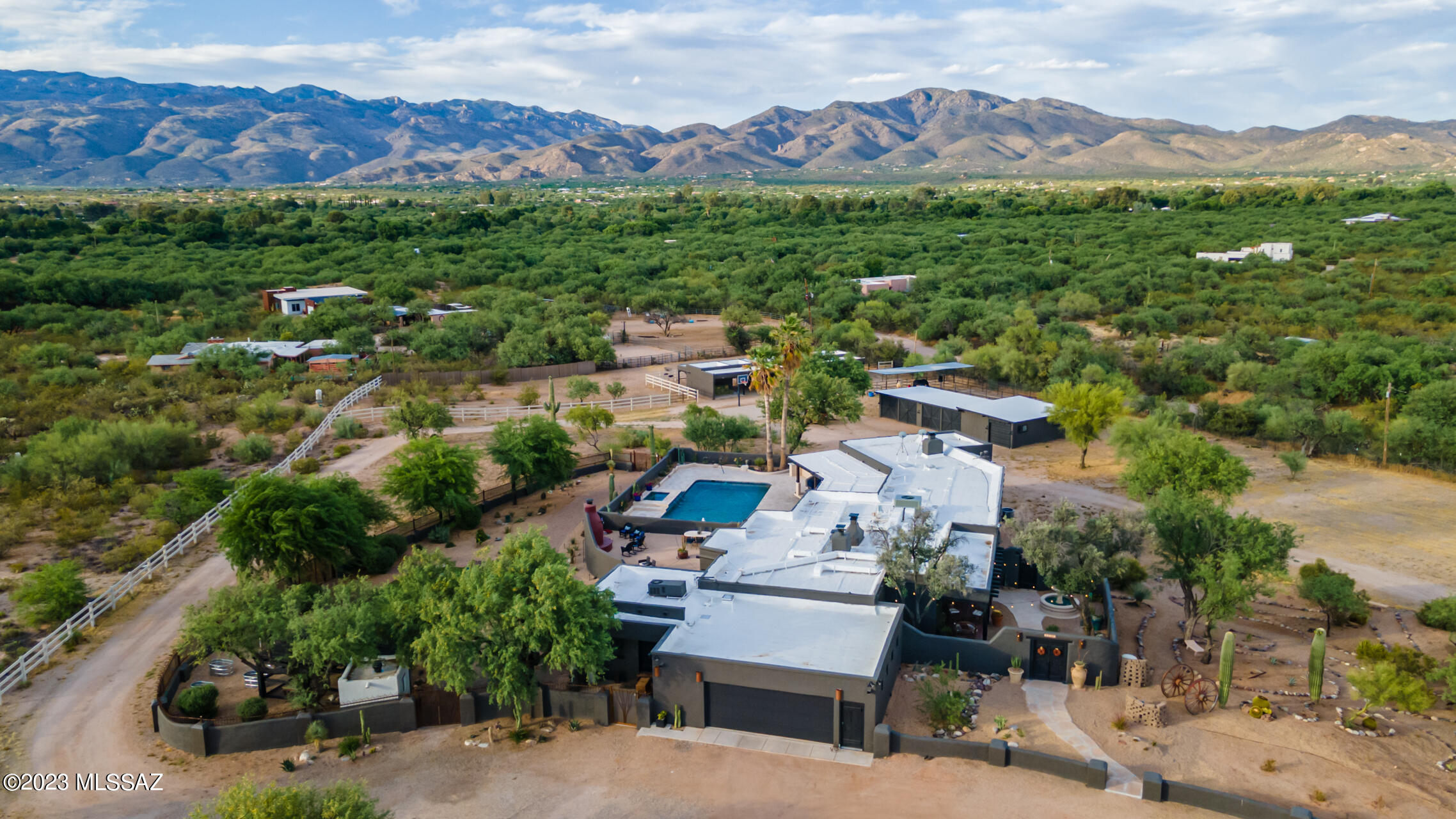 Welcome to this historic adobe & concrete block constructed estate sitting on 4.25 acres surrounded by unobstructed mountain views with direct wash access. The main residence, guest house, 5 bay garage/workshop (mancave) 4-stall block equestrian barn, tack room, 3 additional covered stalls, turnout  have all been thoroughly & lovingly updated with modern conveniences while retaining the historic charm. All of the hard work has been done including updated electrical, plumbing, windows, roof, HVAC and tankless hot water heater. This home is located in the A+ rated Tanque Verde School District and allows you to enjoy the charm of country living while only being 2 miles from shopping, dining & so much more! Connected to both city water and a private well. The main home features hand hewed beams from Mt. Lemmon along with custom doors throughout, added by nationally recognized local builder Mark Butler. The outdoor living space is a desert oasis that has been refreshed for the ultimate entertaining. Spend time relaxing by the pool or shoot some hoops on the basketball court. This property is a horse lover's dream and has direct access to the wash for miles of trail riding, hiking & biking into the Saguaro National Forest. Along with the wash access, there are 4 indoor/outdoor stalls that offer a significant temperature difference on the hot summer days & cool winter nights. These 4 stalls have automatic waterers in all paddocks & open directly into a newly fenced turnout. There are 3 additional spacious covered stalls. The newly constructed chicken coop is within the fully fenced in backyard for easy access to fresh eggs. Additional custom iron fencing provides ample space for the dogs to run & a second layer of protection for the chicken coop.
