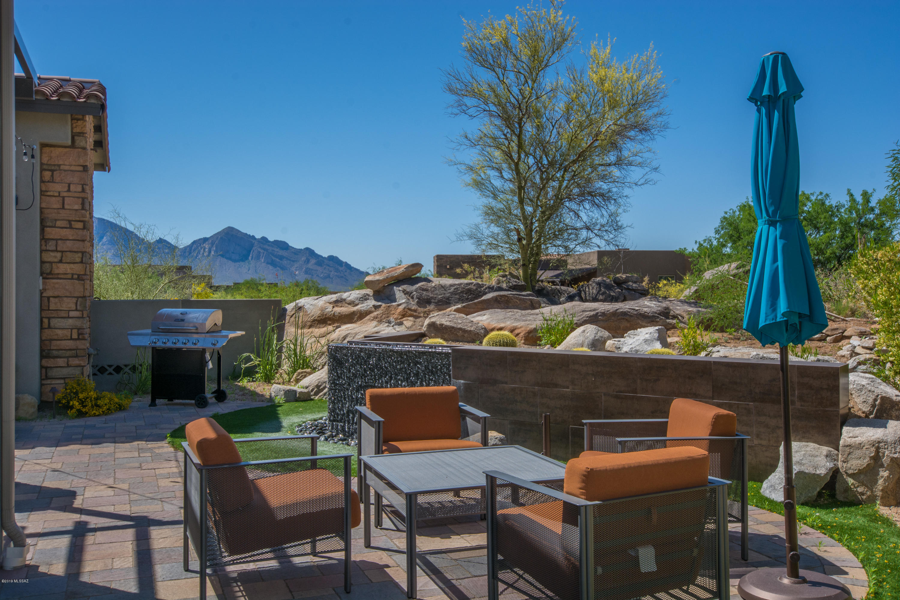 Stone Canyon views from all directions are yours in this beautiful former model home! The gated, entry courtyard w/water feature offers dining & entertaining space w/ access to game room, wet bar, wine storage, DW, 1/2 bath & glass roll up door.(could also double as another BDRM). Glass entry doors open to great room, dining & kitchen. Plank tile flooring throughout. Cathedral ceiling, fire feature & telescoping sliding glass doors open  to stunning views, sparkling pool & water features. Gourmet kitchen boasts large island w/seating, plenty of cabs & silestone countertops,  Wolf & SubZero appliances, walk in pantry. Secluded master, dual sinks, walk-in shower, 2 closets. Office/den w/patio access. BR2 features walk in closet. Laundry has sink, cabs for storage. FURNISHINGS INCLUDED !!!