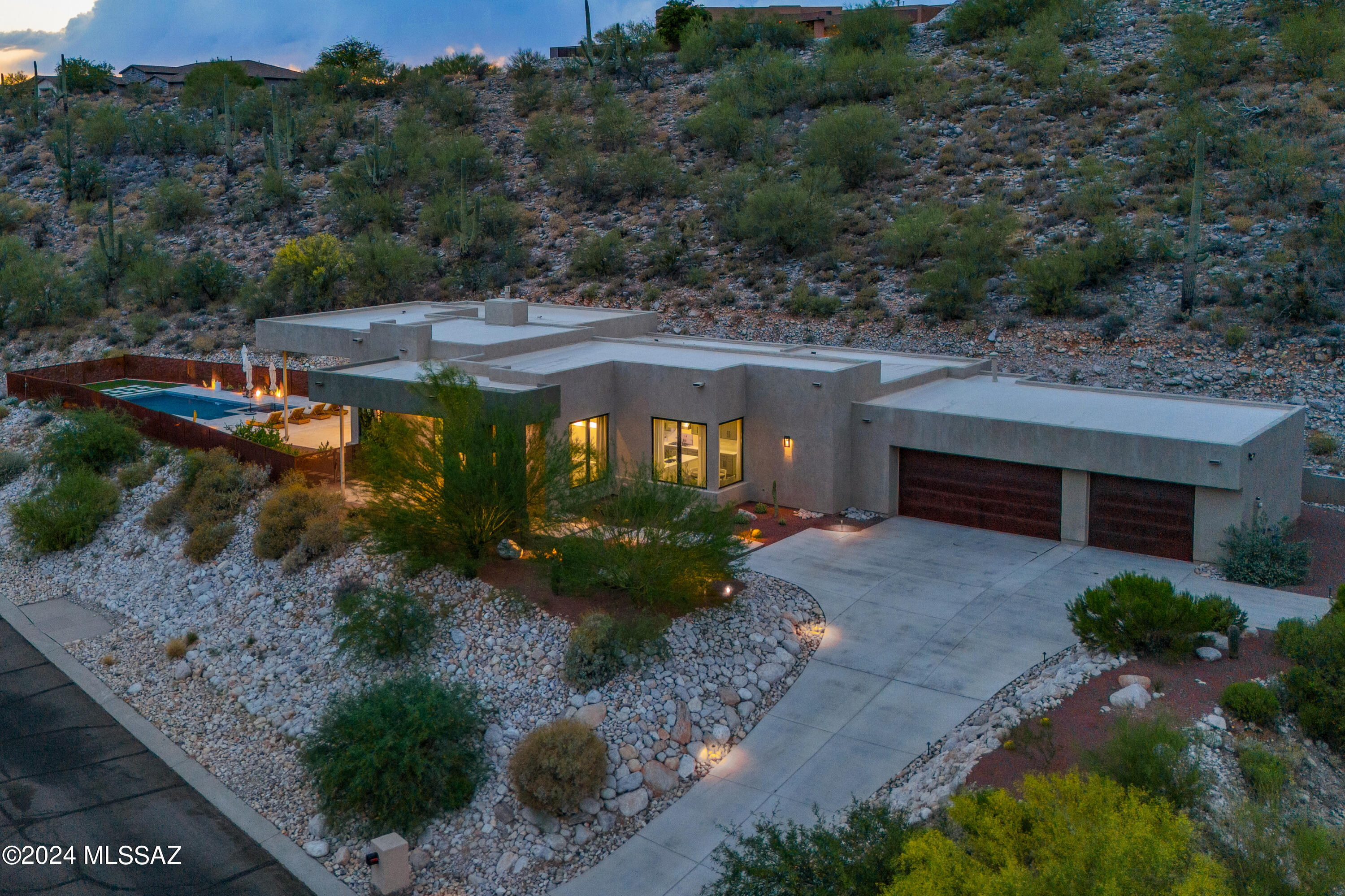 Welcome to an exquisite sanctuary in the prestigious and gated Sabino Mountain community. This modern Sonoran masterpiece is designed to captivate with its breathtaking views, elegant modern architectural features, and flair.

Upon entering, you are greeted by expansive window walls that perfectly frame the awe-inspiring vistas of the Catalina Mountains, shimmering city lights, and the distant beauty of the Santa Rita Mountains. This home offers a seamless blend of indoor and outdoor living, with designer lighting and stained concrete flooring throughout, enhancing its sophisticated ambiance. Spanning 4 bedrooms and 3.5 baths, this residence ensures comfort and privacy. Three of the bedrooms feature en-suite bathrooms, providing a lavish retreat for family and guests. The expansive master suite features his-and-her custom closets, and a luxurious bathroom equipped with a free-standing tub, a walk-in shower, dual vanities, and a dedicated make-up station.

The heart of the home is its state-of-the-art kitchen, meticulously designed for the culinary enthusiast. It features top-of-the-line Viking stainless steel appliances, a custom built-in coffee bar, a massive waterfall island, quartz countertops, and a butler's pantry. This space seamlessly transitions into the living area with a full wet bar perfect for relaxing or entertaining by the stylish fireplace - all while soaking in the magnificent views. 

Step outside to your private oasis via 10ft multi-panel doors that open to the patio where luxury knows no bounds. The backyard is a paradise with a sparkling pool and temperature-resistant pavers, ensuring comfort and style under the Arizona sun. Entertain family and friends with ease using the outdoor pizza oven and grill, perfect for al fresco dining.

Experience the epitome of luxury living at 4131 N Sunset Cliff Dr., where every detail is curated to offer unparalleled comfort and elegance amidst the stunning mountain backdrop. Your next chapter starts here!