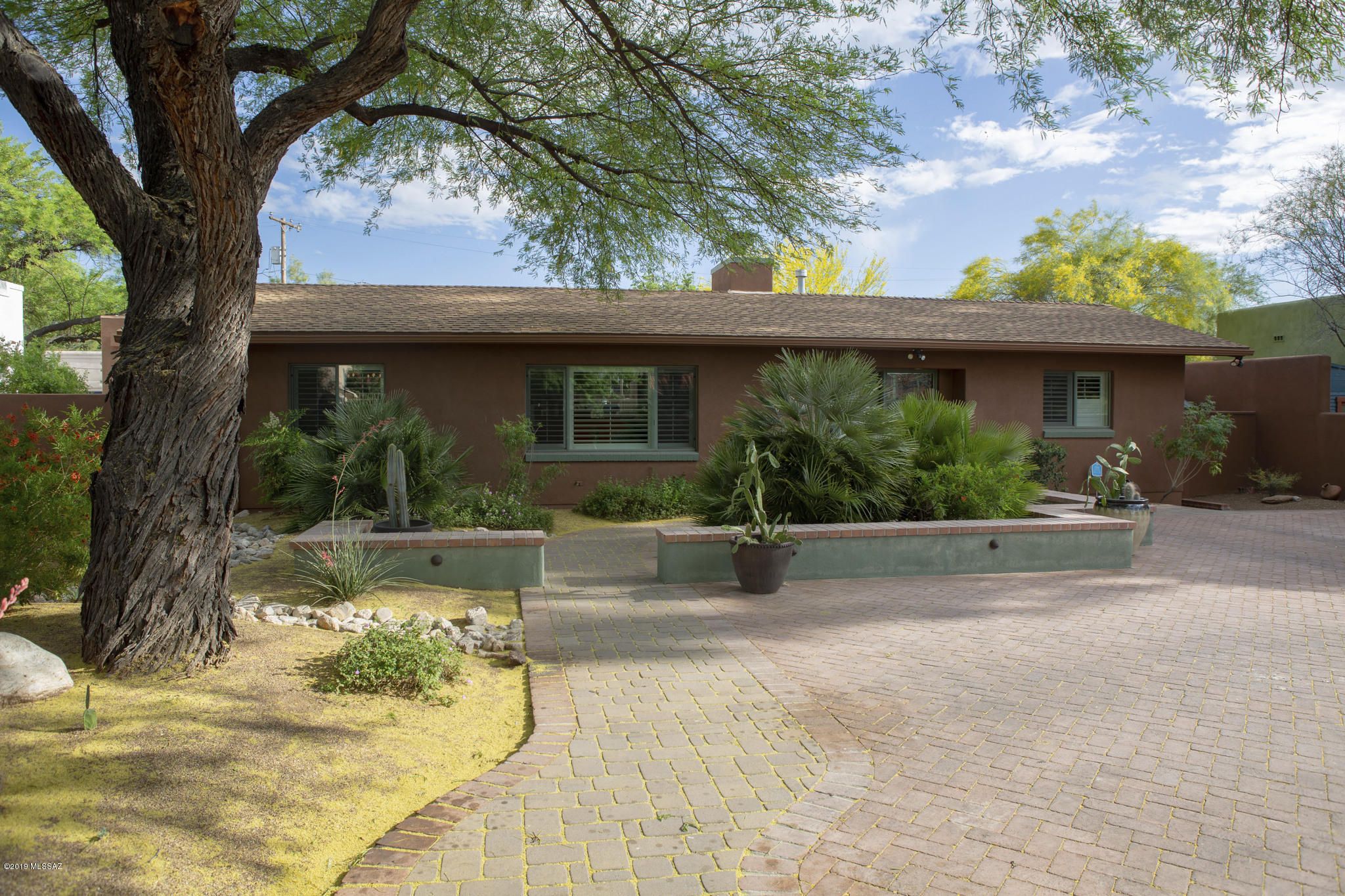 This immaculate & completely remodeled home is located on a fantastic lot within historical Sam Hughes, less than a block to the University of Arizona & the 3rd Street Bike Blvd. From 2012 until today just about every surface of this 2,536 sqft split floor plan, 3 bedroom, 2 bathroom & detached 1 bedroom, 1 bathroom, 299 sqft Guest House has been renovated, refurbished or replaced with superior quality & attention to detail.
As you enter you are greeted by a beautiful artistic stained glass window by Ochoa Stained Glass in entry beside the new front door. The large living room features a brand new custom built wall to wall book case, gorgeous hardwood floors, plantation shutters, custom mantle over the freshly painted fireplace & a brand new chandelier in the dining area. Completely remodeled kitchen including all new Kitchenaid appliances, new cabinets, custom made island & new quartz countertops.

There is a beautiful flow to the house. Adjacent to the kitchen sits the family/Arizona room with new tile & wonderful look at the courtyard. From the kitchen & down the spacious hallway featuring plenty of cabinets sits awaits an absolutely fantastic Master Suite. The same hardwood floors are featured in this large bedroom which also has an adjacent private walled in patio, walk in closets & a master bathroom to behold. Two custom vanities, brand new tile, walk in shower, new rainglass windows & a freshly glazed clawfoot tub.

The two large guest bedrooms also include the hardwood floors & the guest bathroom has new countertop and beautiful custom tile work. The guest house has also been completely remodeled with a Murphy Bed, built ins, new flooring throughout, new kitchen cabinets, new microwave & dishwasher, AC system, new bathroom vanity & sink. The entirety of the interior of both the main house & guest house has been painted. New AC system, new hot water heaters & another refrigerator available in the large laundry room.

Parking is at a premium in Sam Hughes. The entire property is walled in, with 2 electric gates, one in the front & an alley entrance. A gorgeous brick paver driveway has enough space for 4 cars.  The back alley entrance has a brand new 4 car carport.

Enjoy the best of Arizona outdoor living. The curb appeal from the street is extraordinary with the newly professionally landscaped yard. The backyard is equally as amazing featuring a Lanai off Arizona Room with a brick paver patio & a new gas fire pit surrounded by banco seating. Remember the new 4 car carport? A few tables, some seating & lighting overlooking the patio & fire pit & you have transformed the backyard into a spectacular entertaining space!