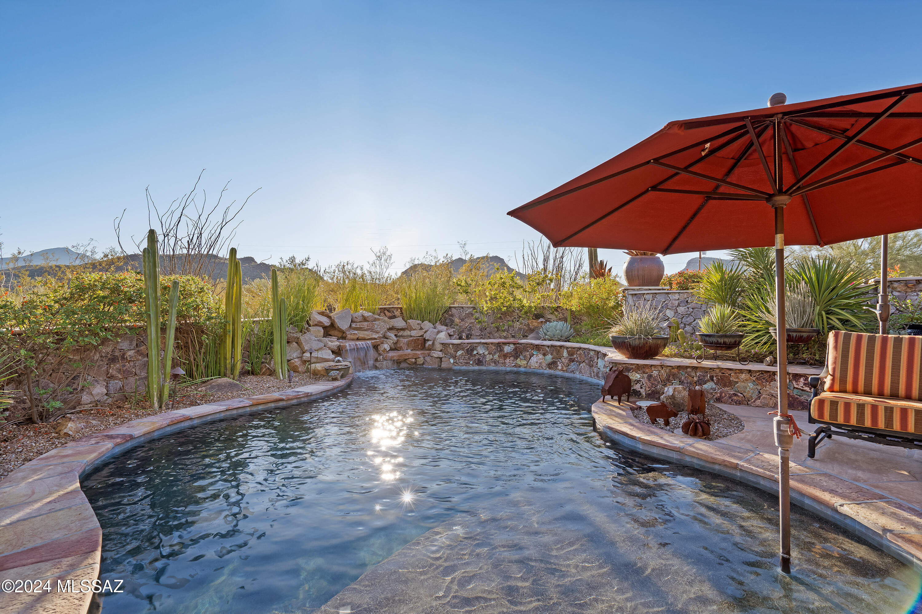 Range priced between $1,650,000 to $1,700,000. Breathtaking custom Santa Fe-style retreat, nestled on 7 acres of serene desert landscape w/ panoramic mountain & sunset views. This luxurious 4-bedroom, 4-bathroom home features a MOVIE THEATER w/ custom seating, a massive BONUS ROOM or GUEST QUARTERS w/ kitchenette/wine fridge, & lavish decor throughout. The elegant flagstone entryway leads thru arched wood doors to a bricked courtyard w/ fountain. Step inside to a a beautiful foyer, Travertine floors, crown molding & hickory doors throughout. The chef's kitchen w/ granite counter tops boasts top-of-the-line KitchenAid appliances, a gas range, breakfast bar & new microwave,oven & warming drawer. Incredible backyard w/ botanical garden like landscaping & walk around courtyard.. Outdoor kitchen & gorgeous pebble-tec pool w/ waterfall. Unwind in the primary suite, complete with a spacious walk-in closet & a private sitting area w/ incredible desert views. With two cozy fireplaces, custom draperies, custom painted interior & fine finishes at every turn, this home offers a blend of sophistication & warmth, perfect for those seeking privacy & luxury in the heart of nature. Recent updates include new reverse osmosis system, new soft water system, recoated roof w/ warranty, new kitchen appliances, newer dual HVAC units. List of extensive renovations completed since owner bought home available. Gated enclave w/ no HOA, near Saguaro Park and many walking trails, this one of kind home is a must see!! All furniture including patio furniture & decor is available. Can be completely turn key!