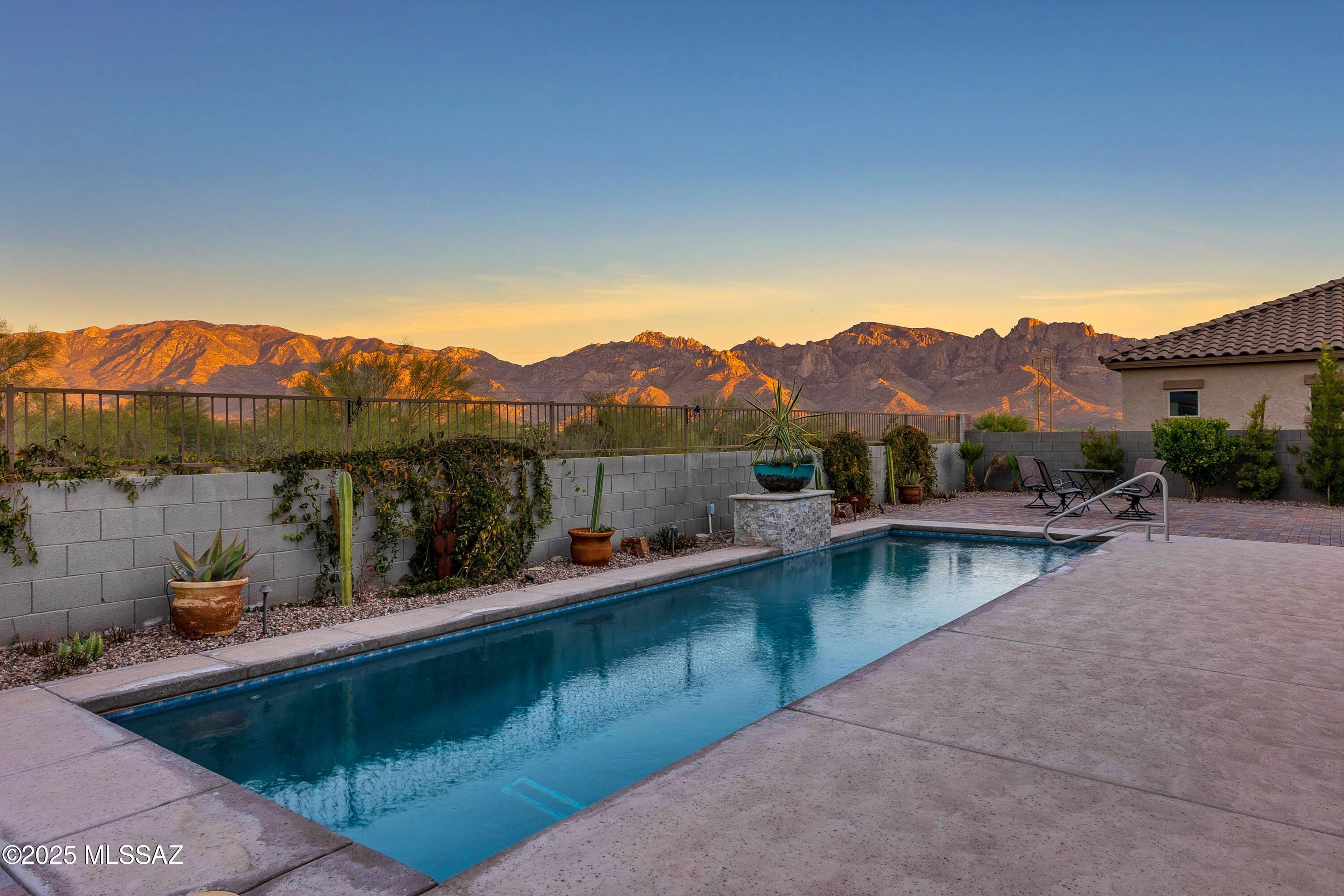 This home is situated in the heart of Oro Valley, backing up to protected open space where you can take in the unobstructed views of the Catalina Mountains. This newer 2019 build is 2,404 square feet, 3 bedrooms plus a den, 2.5 baths, a gourmet kitchen, and a large primary suite with an extended shower. You can enjoy access to a paved walking trail in the community for morning exercise or sunset strolls. The previous owners were meticulous in choosing upgrades that most people forgo, and we are sure that you will appreciate them all! Starting at construction, rather than the typical 5' setback, they opted for an oversized lot, allowing a 10' setback in the side yards and providing extra space between homes for walkways, landscaping, equipment, storage, and privacy. Additionally they added the bay window in the master bedroom with coffered ceiling, central vac, extended 2' in garage, cat 6 cable wiring throughout, tankless recirculating water heater, large back patio sliding doors, kitchen appliance and cabinet upgrades, flooring upgrades and pre-plumbed soft water/hot water loops with cold sink and refrigerator bypass. After construction, they went on to add the exquisite finishing touches  Lap pool with extended patio, landscaping with additional wall, low voltage lighting, plantings, 4 zone irrigation system (back), 3 zone irrigation (front) and pavers. Full gutters with drainage to the front, high end fans in all major rooms and outdoor patio, Hunter Douglas and sun blocking powered window coverings and shades, epoxy garage flooring, widened front driveway with front to rear pavers, water softener. All this in a gated community. 
This home has it all. The views are SPECTACULAR!