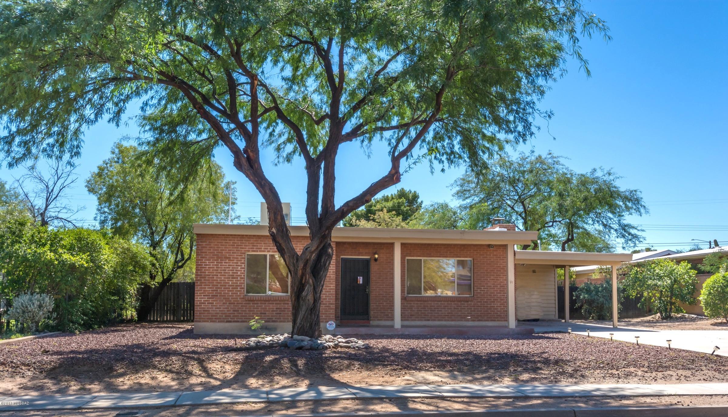 This tastefully updated, move-in ready 1950's home in Central Tucson is brimming with character and charm and accented with beautiful high wood beamed ceilings and flagstone wood burning fireplace.  Plenty of windows bring in tons of natural light.  Open island kitchen and tile floors throughout (except bedrooms).   Huge fenced in backyard with mature trees, full length covered patio has 2 ceilings fans and good sized storage shed.   Nicely finished laundry room off carport with additional storage.  Just minutes from the U of A and Banner Hospital.  Fantastic curb appeal and situated on an extraordinarily large .27-acre lot.     Show with pride, contract in hand and act fast because this one won't last!