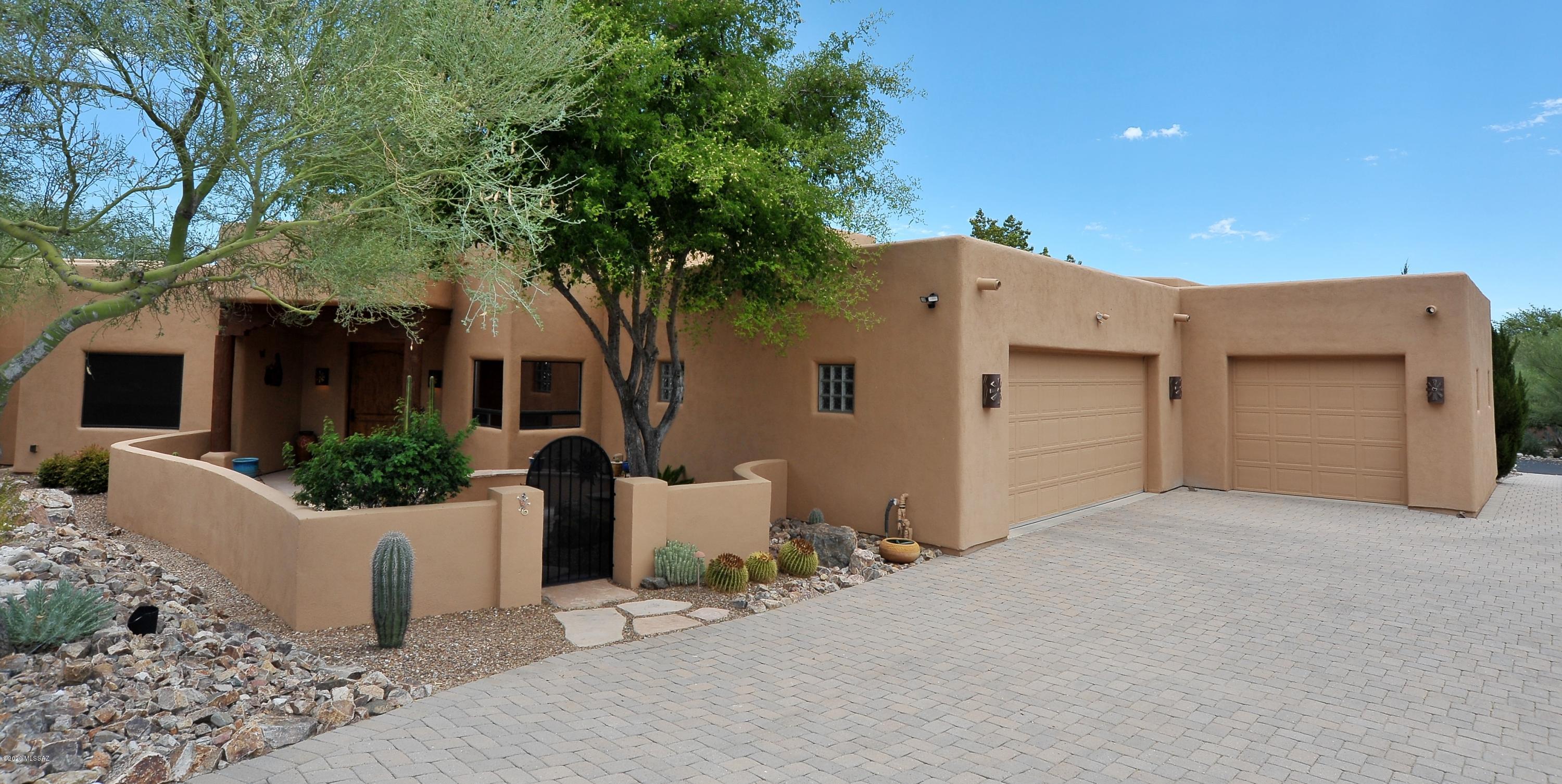 Magnificent Santa Fe style home featuring an impressive rock fireplace and authentic viga-latilla ceilings. Family room, living room, bar, dining room and kitchen all radiate from this central feature. Impeccable maintenance and tasteful upgrades including granite tops in the kitchen, newer appliances, fresh paint, re-finished flagstone floors, and hardwood in all bedrooms, see documents tab for full improvement list. Custom Philabaum glasswork graces the den and master suite doorways. Lush yet easy care outdoor spaces with tranquil fountain and plenty of room for a pool if desired, all with spectacular mountain and city views. Easy access to downtown, I-10, and endless hiking activities at your doorstep with Tucson Mountain Park access nearby.