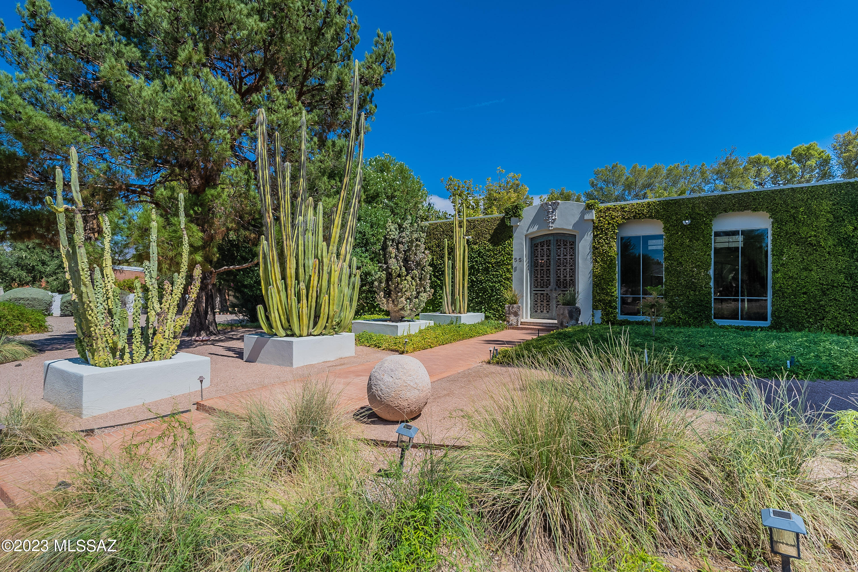 Introducing a master class in design and effortless beauty. Don't miss this unique home inspired by nature and fearless architectural lines, this home site is unique to Tucson's rich history. Craft-fully designed by the homes owner's along side notable landscape architect Guy Greene, immense pride of ownership has remained since its inception. The feeling is inevitable once you arrive. Fresh gardens and fig vine greet you and hug the picturesque facade, The steel and bronze gates welcome you. A wonderful alcove entry with arched alder doors then lead you to a wood beam lined great room, the perfect place to bring your guests and friends. With two large master suites and two flexible spaces the home offers different options for lifestyle. Kitchen and dining are classy and functional. Detail galore! From the faux finished walls and mirror lined dining room, to the concrete floating hearths and silver/gold leaf ceilings all to be admired. Limestone tiles run consistently throughout this one level home adding cohesion and elegance. Natural light is on display at all hours of the day creating a magnificent indoor/outdoor flow. The livable Atrium at the heart of the home allows access from all rooms and an open door or window creates refreshing cross breezes that further exemplify the thoughtful design. A study offers tapestry clad walls, custom built-in alder cabinetry and an en-suite bathroom that exudes luxury and timeless elegance. The generous primary suite features a large fireplace and floor to ceiling windows with views of the secluded backyard. The primary bath offers a jetted soaking tub, multiple walk-in closets, double vanity, custom makeup vanity and is clad in cut marble. The secondary suite includes a large bath with black honed quartz counters and two basins. Rounding out the rooms is a flex space (currently used as an office) that offers another en suite bath that is marble and mirror lined floor to ceiling. The home is wrapped in non-invasive Fig vines creating incredible curb appeal and lush backyard landscape that's a show-stopper! An architectural steel ramada perfectly rests between the pool and grass landing offering a place to lounge and play. Parking is also generous with an aggregate and brick motorcade, as well as a formal and finished 2-car garage that could be purposed for fitness or studio use. Designed to entertain, the outdoor spaces of this ultimately private residence is truly bar none. A wonderful property and opportunity within reach of the U of A, Banner Medical and the Arizona Inn all together in the heart of Tucson.