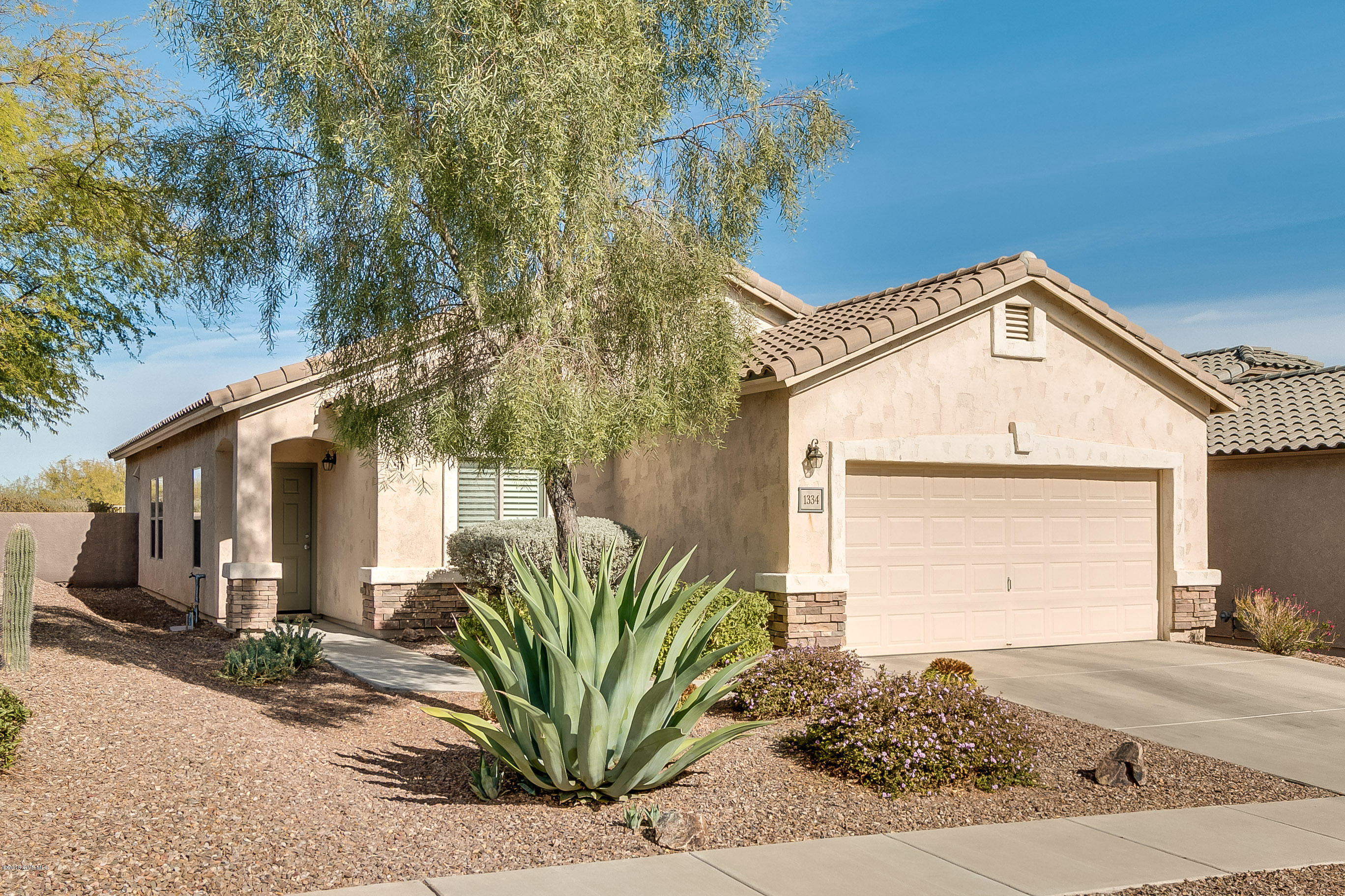 Cascading roof lines combine with desert landscaping and a slate rock veneer display elegance and charm. Your adventure begins in the open floor plan with living room and dining set with beautiful tile flooring. The dining area is conveniently adjacent to a large pass through window with easy folding shutters to offer separation from kitchen activities. Your generous kitchen is designed for effortless meal prep with its abundant counter space, gas range, and corian countertop with integrated sink for easy cleanup. The staggered height cabinetry capped by crown molding, almond appliances and room for kitchen table will deliver additional features that you will love. Catch up on some computer work or relax with a novel in your quiet den with its convenient pull-down Murphy bed  for occasional overnight guests. Relax and take-in the desert air out on the back patio overlooking natural open space where earth tone brick pavers create an outdoor experience incorporating an open-air living room and dining area. A wrought iron fence with soft lighting will enhance your evening ambience. A beautiful home indeed!