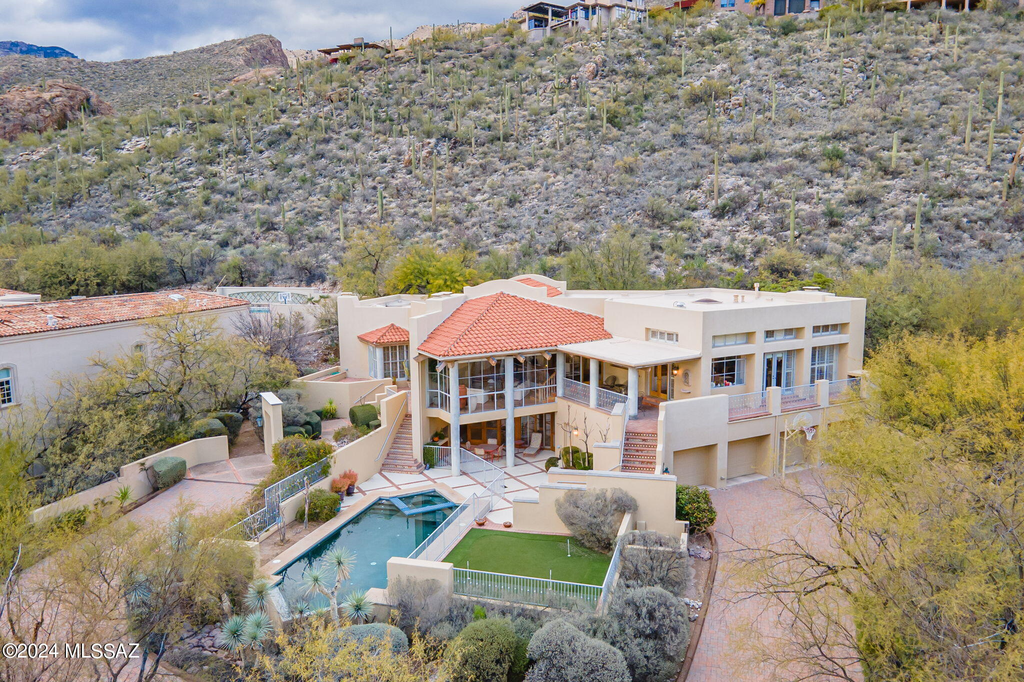 Architectural Warmth & Character Exude in this 5 BR & 5 BA Contemporary Home Perched High In The Coveted Guard Gated Community of Ventana Canyon. This Exceptional Multilevel Home Filled w/Natural Light Offers Walls of Windows Showcasing Mountain & City Views. Fine Features Include: High Wood Beamed Ceilings & Brick Floors - Open Formal Living & Dining Areas  w/Wet Bar & Grand Fireplace - Island Kitchen w, Balcony, & Outdoor Covered Dining Area - Great Room w/ Fireplace Opens to Kitchen - Primary Suite w/ Sitting Area & Fireplace, Spa Like Bath w/Sunken Shower & Jetted Tub - Upstairs Guest Rooms w/Built in Desks, Wood Floors,  & Jack + Jill Bath w/ Private Vanities - Library/Den - 2 Lower Level En-Suites - Private Outdoor Living Area w/Pool, Spa & Putting Green -  Spacious 4 Car Garage..