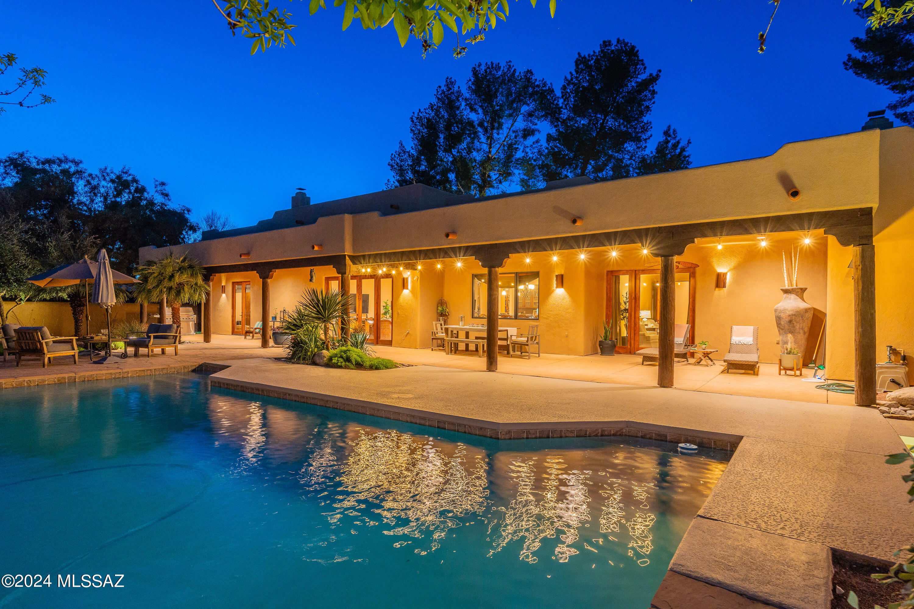 Southwestern contemporary (built in 2006). Gated community within Tucson Country Club. This home is 4,779 square feet (including a 425 sq ft guest house).  High-quality materials and finishes throughout, soaring wood-beamed ceilings, scored concrete floors, stacked stone fireplace, custom knotty alder cabinetry, Travertine backsplash, stainless steel appliances. Chef's kitchen with a large center island and breakfast bar, two wine coolers, under counter microwave. Massive glass and wood double doors, iron accents, gracious formal dining room, great room. Mature trees, circular driveway, courtyard entry with tiered fountain, covered patio, stunning mountain views, pool, and hot tub.