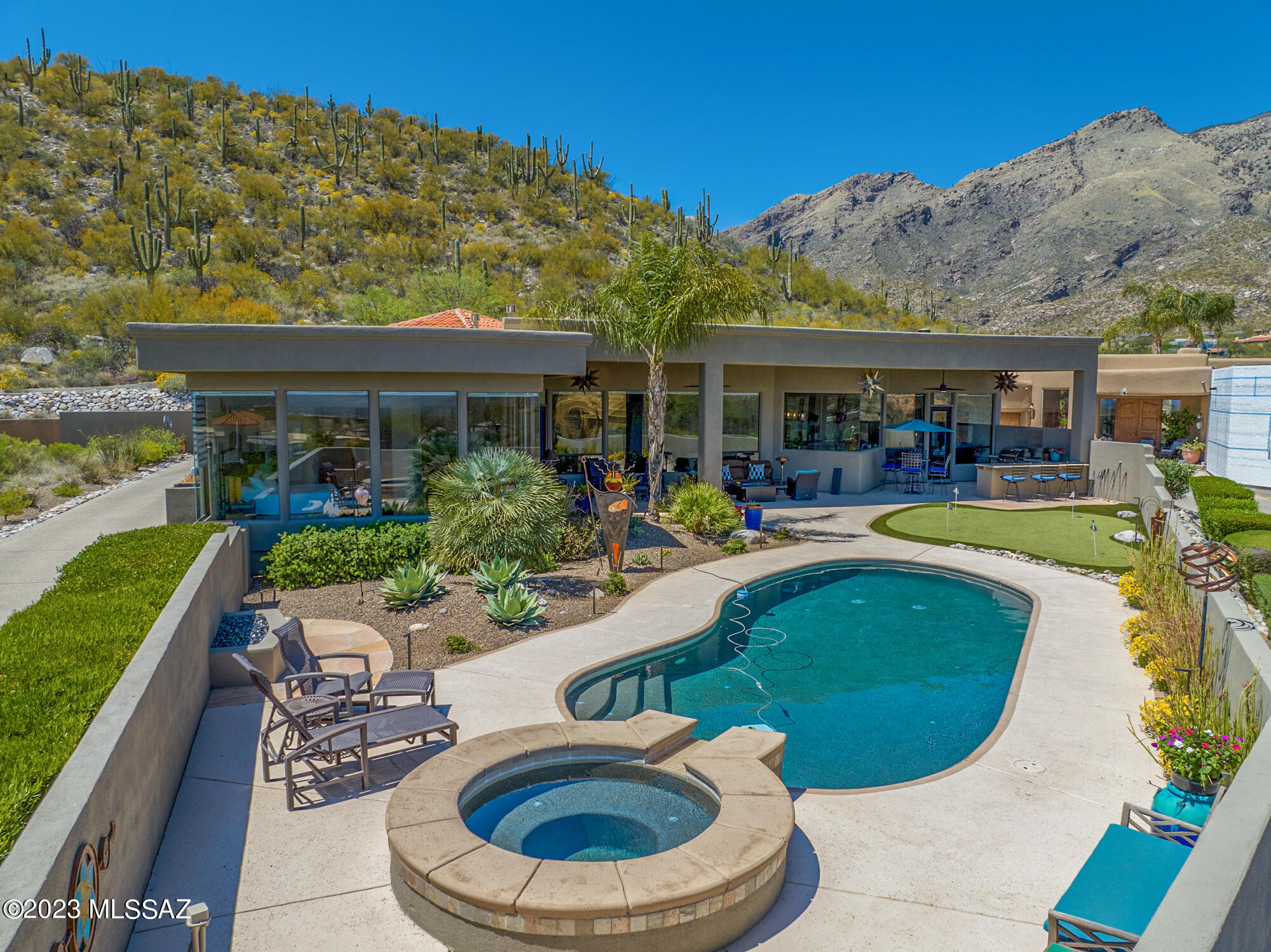 Welcome to this stunning 5 bed/5 bath, 4880 sq ft. home nestled high in the Catalina Foothills in the prestigious Alta Vista neighborhood. The home sits on an elevated perch providing breathtaking 360 degree mountain and city views. Seamless inside/outside resort living with an outdoor built in kitchen, putting green, covered patio and solar heated pool/spa.  Step inside and be welcomed by the spacious and inviting living area enveloped in natural light, soaring ceilings, floor to ceiling picture windows, and an open floor plan that is perfect for entertaining guests or spending time with family. Luxury custom-designed gas fireplaces in the living and family rooms are perfect for relaxing on colder Tucson nights. Electric remote-controlled blinds in kitchen, living room, family room and primary bedroom. The gourmet kitchen is a chef's dream, featuring top-of-the-line stainless steel appliances, custom knotty alder cabinetry, ample storage space, and a center island with generous seating and a built-in sink. Split floorplan with the primary suite featuring world-class views, custom gas fireplace, spacious en-suite bathroom with a whirlpool tub, walk-in shower, double vanities and walk-in closet. The additional 3 bedrooms are generously sized with walk-in closets and en-suite bathrooms. The 4th bedroom makes a great office space or additional bedroom if needed. The hobby/game room is an ideal space for family game night or a bridge game with friends. The oversized 3 car garage comes fully equipped with a 220V electric vehicle power supply and abundant storage throughout. Just minutes from Ventana Country Club, hiking trails, shopping, and dining. With its stunning design, luxurious amenities, and prime location, this home is the perfect place to live your best life in Tucson.