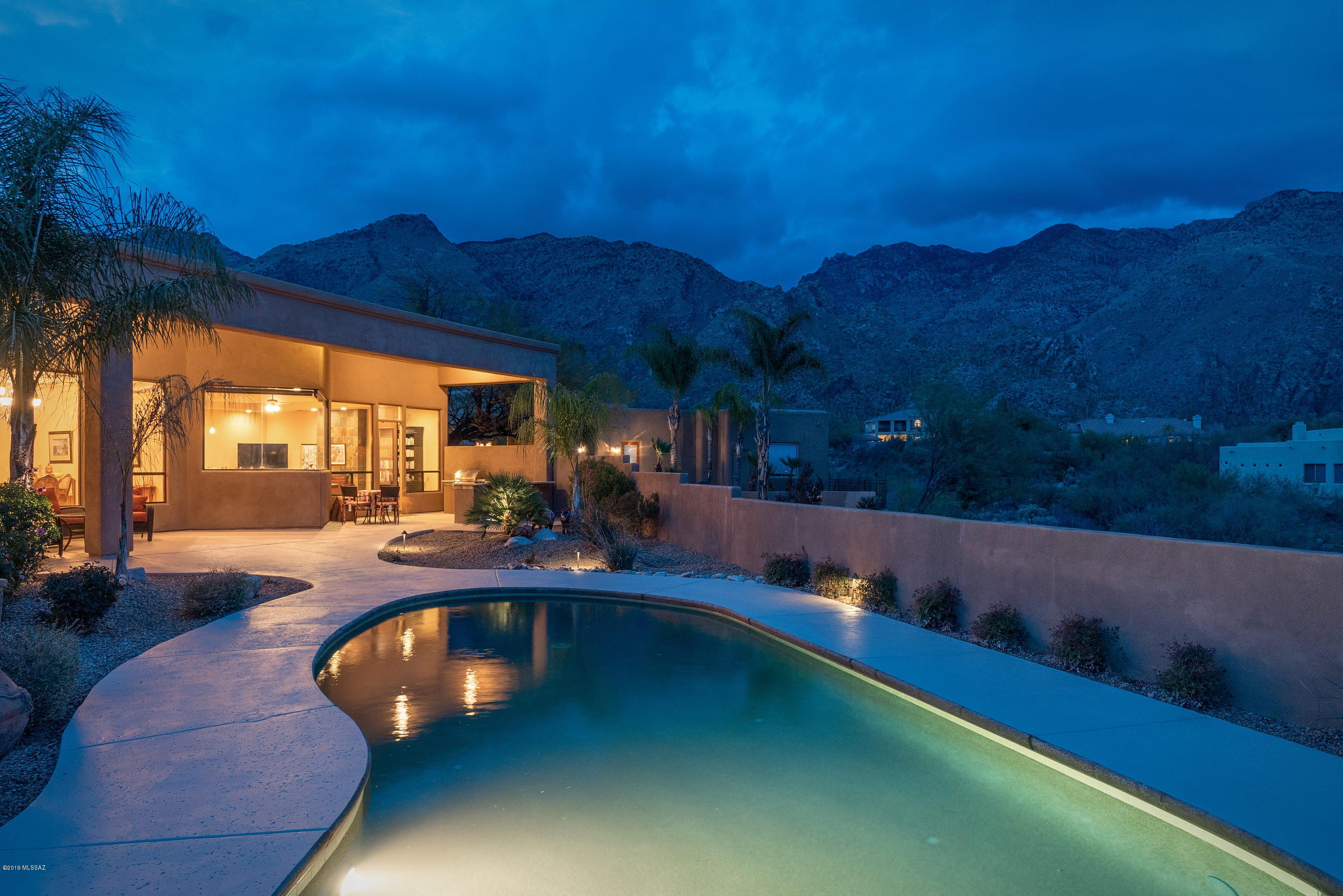 Nestled within the prestigious Alta Vista Community offers an oasis of serenity, luxury and unwavering attention to detail. This stunning home possesses a refined fit and finish level felt immediately upon entering the home. Take notice of the dramatic ceiling heights, structurally utilizing cantilevered support beams, eliminating the need for columns, allowing natural light to filter through an array of large picture windows, framing the Catalina Mountains beyond. Move past the foyer to find the grand scale living, dining and family rooms opening onto the gourmet chef's kitchen, featuring top end stainless steel appliances, custom knotty alder cabinetry, granite counter tops and a high quality continuity of millwork carried throughout the property. The layout lends itself to entertaining family and friends alike, offering a split bedroom concept, with the master suite sequestered on the Southeast end of the property captivating it's audience with a large walk-in closet, luxurious bath and windows from the bedroom spilling out over private rear courtyard. The outdoor spaces organize and focus around the Catalina and Rincon mountain ranges as they form a series of spatial engagements, which include a solar heated pool, outdoor fireplace, barbecue station and large covered patio, all there for your personal enjoyment on this premium homesite. The oversized garage comes fully equipped with a 220V Electric Vehicle power supply and ample storage throughout.