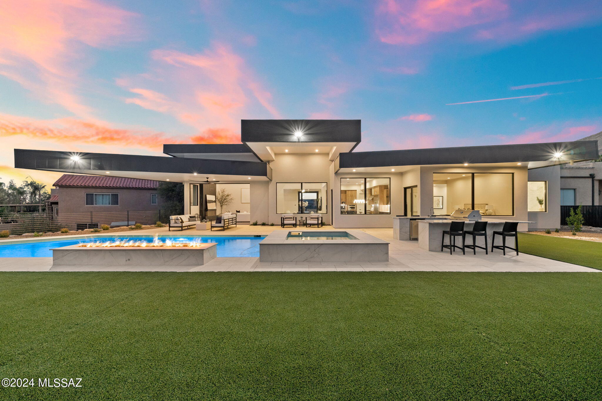 New construction! Presenting a rare offering in the heart of the Catalina Foothills, a modern masterpiece crafted to perfection by master builder, Monty Bartholomew, of Real Exquisite Estates & Properties, who has built some of Tucson's most luxurious properties, and designed by renowned architect Bill Gansline. This 4 bedroom, 4.5-bathroom home offers a sophisticated fusion of design, luxury, and comfort in one of Tucson's most sought-after locations.

Upon entering the property, you're welcomed by a stunning glass entry pivot door that leads you to the open great room with soaring 16-foot ceilings and an expansive multi-panel sliding glass door that fully pockets/''disappears'' into the wall. These walls of windows immaculately frame the breathtaking desert landscape and unobstructed mountain views. One of the home's best features is its desirable floor plan that has no interior or exterior steps and each bedroom is complete with its own ensuite bathroom, providing a sanctuary of comfort and luxury for residents and guests alike. 

The chef's kitchen is a perfect collaboration of elegance and functionality, equipped with state-of-the-art appliances, including a 6-burner gas range with griddle, double ovens, hood, refrigerator, and freezer. Top of the line modern European style cabinetry from Affinity Kitchens are featured not only in the kitchen, but throughout the entire home. One of kitchen's most striking features are the premium quartz countertops and the Titanium granite waterfall island. Finishing off the kitchen is a functional bar area with wine refrigerator, perfect for entertaining. 

Outside, you'll discover one of the most spacious backyards, fully landscaped with low-care artificial turf, trees, and a sparkling heated pool and spa. The expansive pool has 4 waterfall features and integrates seamlessly with the striking gas firepit feature. The huge outdoor covered patio with cantilevered roofline provides a dramatic backdrop to host the largest of gatherings. The outdoor kitchen comes fully equipped with a built-in gas BBQ, sink, mini refrigerator, gas burner, and wrap around bar-top seating. Here, you can relax and soak in the views of the desert surroundings. Finishing off the exterior of the home is a spacious 3 car garage and a beautiful paver driveway.  
As a resident of the Catalina Foothills, you'll enjoy the privacy and serenity of one of Tucson's most desirable neighborhoods, known for its stunning views, excellent schools, and convenient access to upscale shopping and dining. This remarkable property presents a unique opportunity to enjoy the benefits of new construction, while enjoying the tranquility of an established neighborhood.