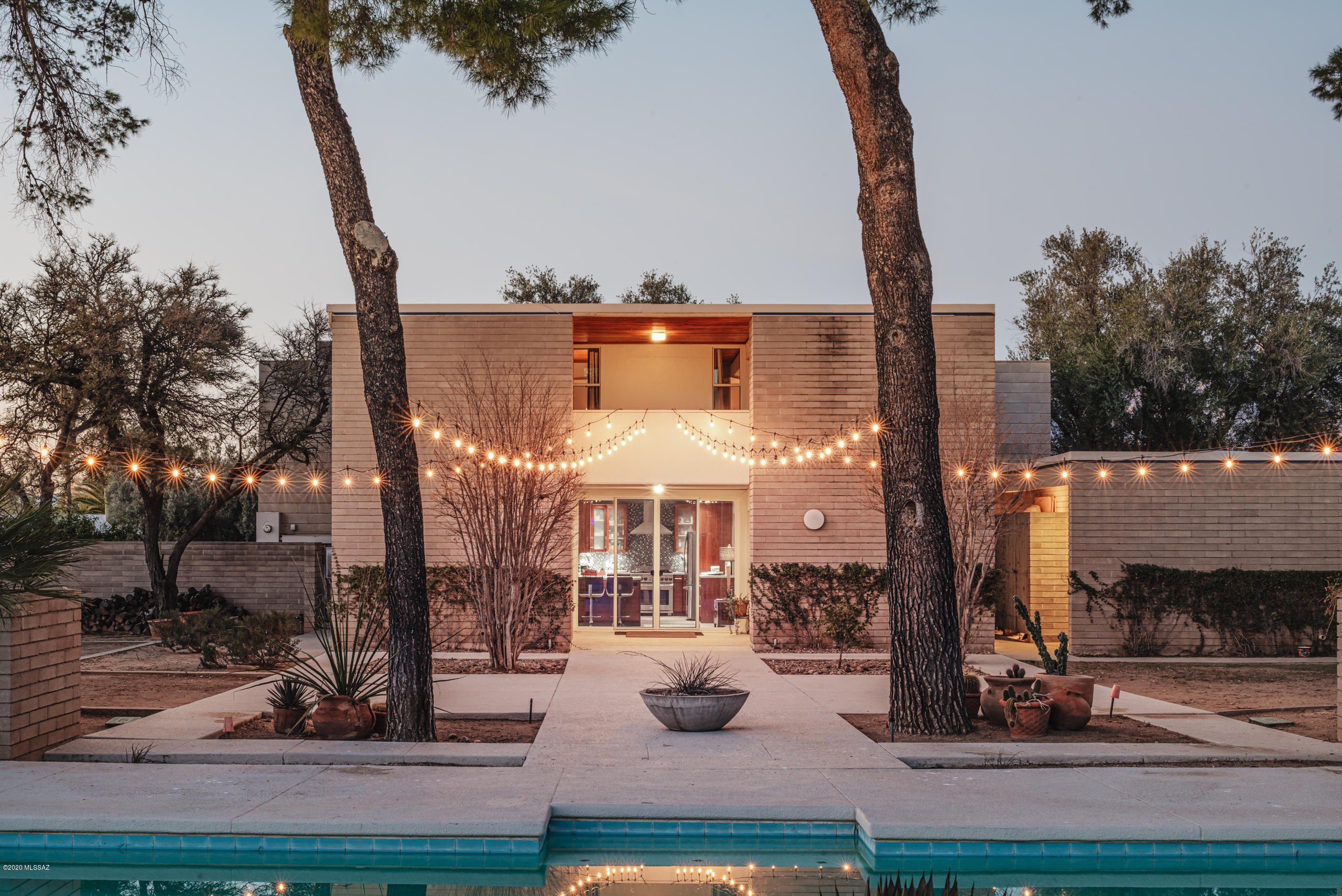 The personal residence of acclaimed architect  William ''Kirby'' Lockard exemplifies the Brutalist Modern style, rarely seen in Tucson. Along with the garage and guest house, designed by second owner Jack DeBartolo Jr. and built in 1978, the residence has been designated a Historic Landmark and rezoning is in process. Featured on the 2017 Modernism tour, the home retains prized midcentury modern details amidst sensitive updates. Beyond a courtyard of old olive trees the entry foyer opens to the formal living room with grand mountain views and custom steel fireplace. Two additional living spaces, a dining area, and magnificent kitchen complete the first floor. The upstairs master suite and two additional bedrooms with a large shared balcony enjoy views of the swimming pool and nearly one ac grounds. The guest house is situated beyond the pool and offers a full bath, kitchenette and extraordinary sliding glass doors.
