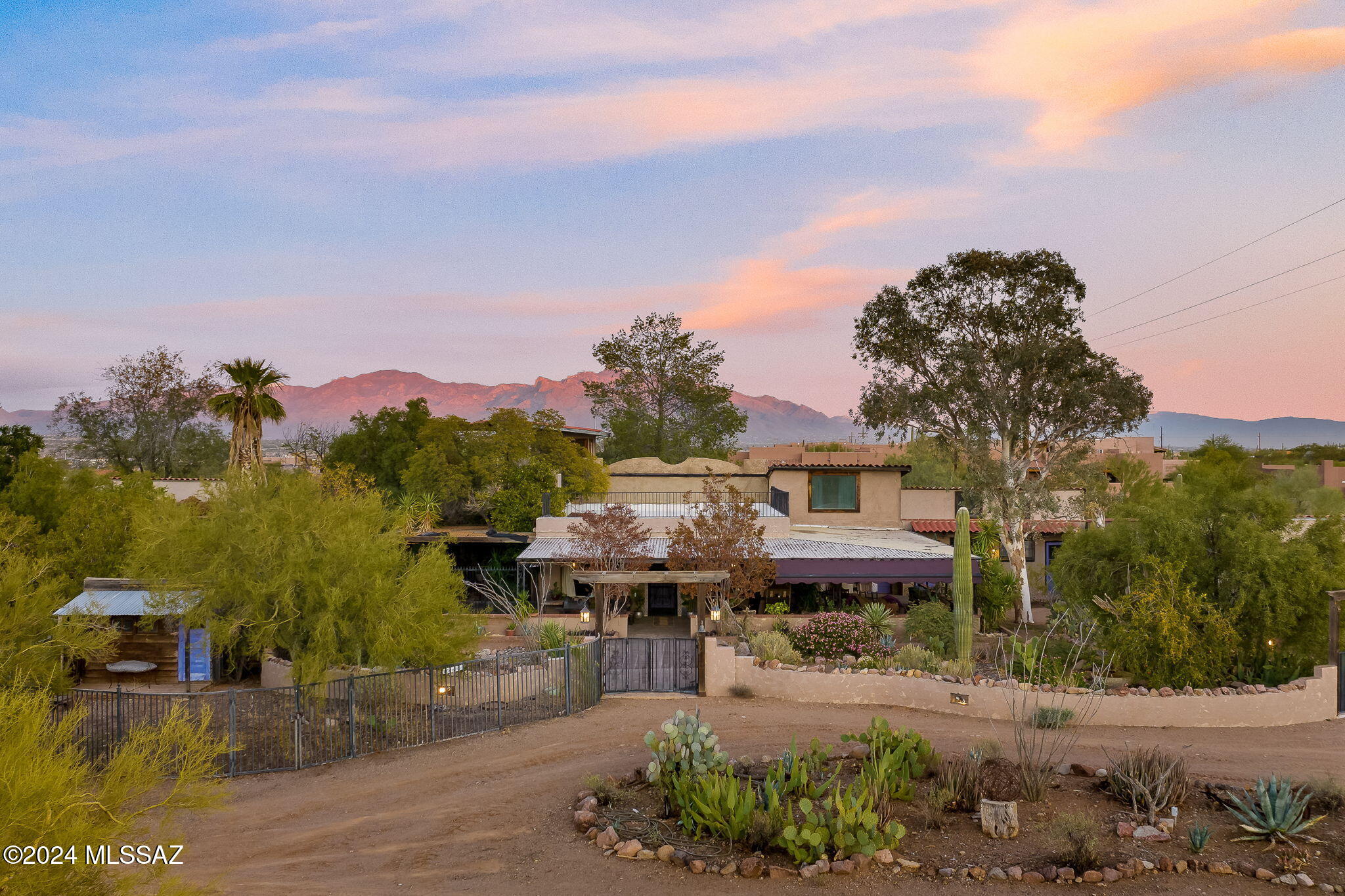 Nestled on 10 lush acres at the base of Safford Peak (Sombrero Peak) in Northwest Tucson, this unique property offers a spacious main home, a private guest house, and stunning panoramic views from the second-floor loft and patio. Perfect for horse enthusiasts, it features stables, a riding pen, and ample open space, all complemented by a sparkling pool and lush vegetation. The property is served by a private 700-foot well, ensuring long-term water security, and is zoned SR (Suburban Ranch), allowing for up to three parcels—ideal for maintaining privacy or future development. This serene retreat combines character, charm, and endless possibilities, just minutes from city conveniences.