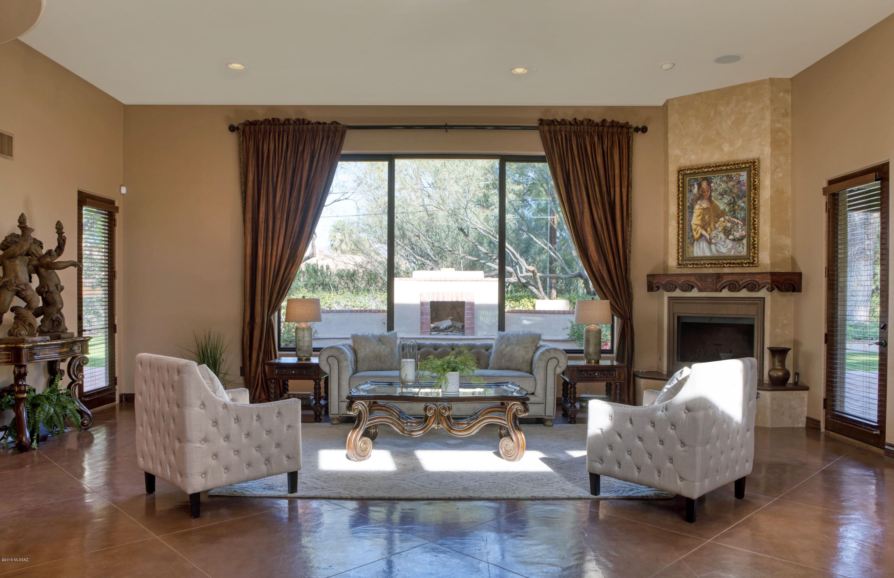 A completely rebuilt and remodeled home in Tucson C. C. with a great room design and soaring ceilings.  Huge mature mesquite trees, a circle drive, Old World iron gates, and a court yard entry with fountain greet visitors.  Concrete floors, French Doors, built-ins and accents from Colonial Frontiers contribute to the character and charm while custom cabinet, slab granite counter tops, and stainless steel appliances provide all the luxury amenities.   Each of the spacious bedrooms has an on-suite bath and walk-in closets.  The master features a fireplace, private patio, his/her vanities, separate tub and shower, and a closet with loads of built-ins.   The huge yard features a covered patio, outdoor fireplace, and expanse of lawn, play area, citrus trees, and mature shade trees.