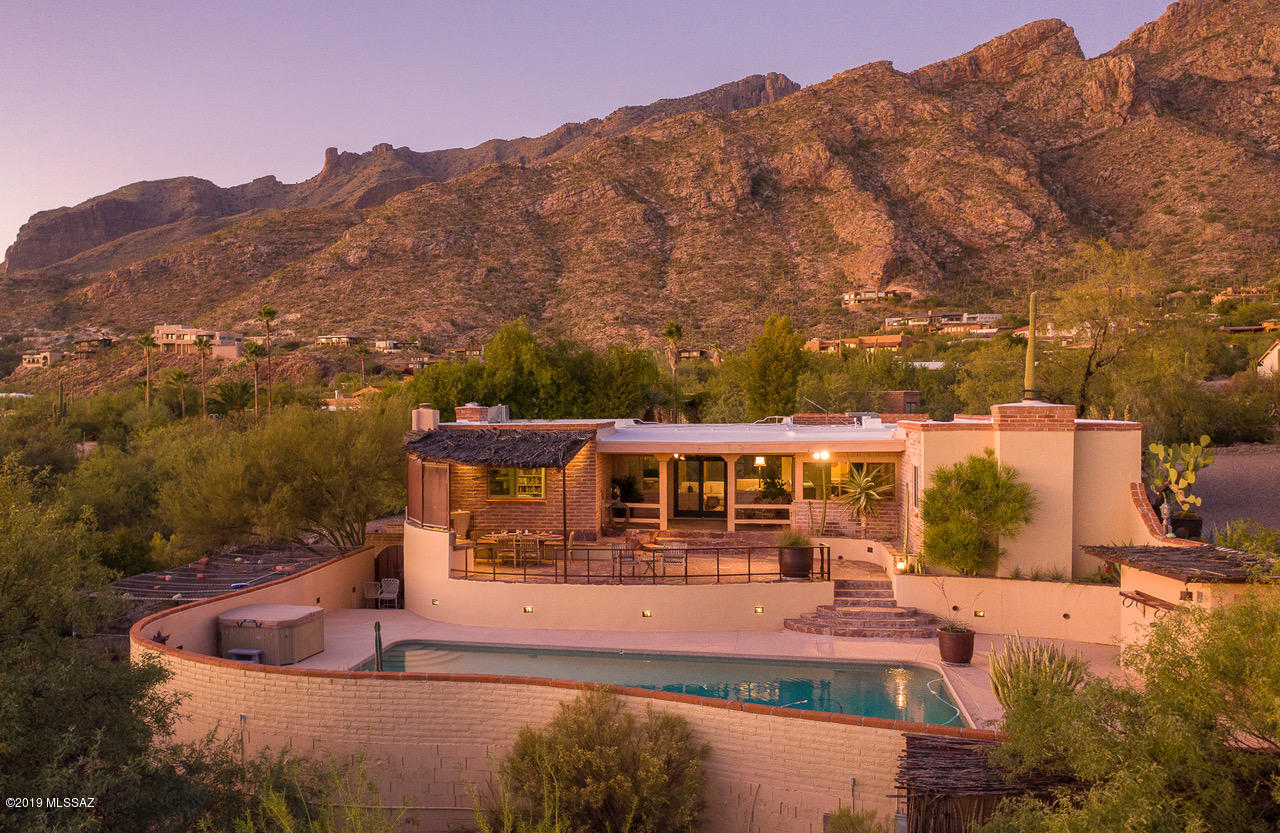 Come see this gorgeous burnt adobe home on a large City Lights & Close-Mountain View Lot in Coronado Foothills Estates. A circular drive leads to the welcoming entry. Inside, the home envelopes with a warmth and character that can be hard to find, while views of the city below and the Catalinas above enchant the eye. The kitchen-family room-breakfast area are the heart of this home, while the split bedroom floorplan is very functional, and the large walk-out basement is perfect for kids, games or hobbies. Modern updated kitchen with stainless appliances. The outdoor spaces are the icing on the cake! Fantastic PebbleTech pool with pool bath sits below a lovely patio with built-in BBQ; while a serene koi pond courtyard makes a wonderful space with the Catalinas towering overhead.